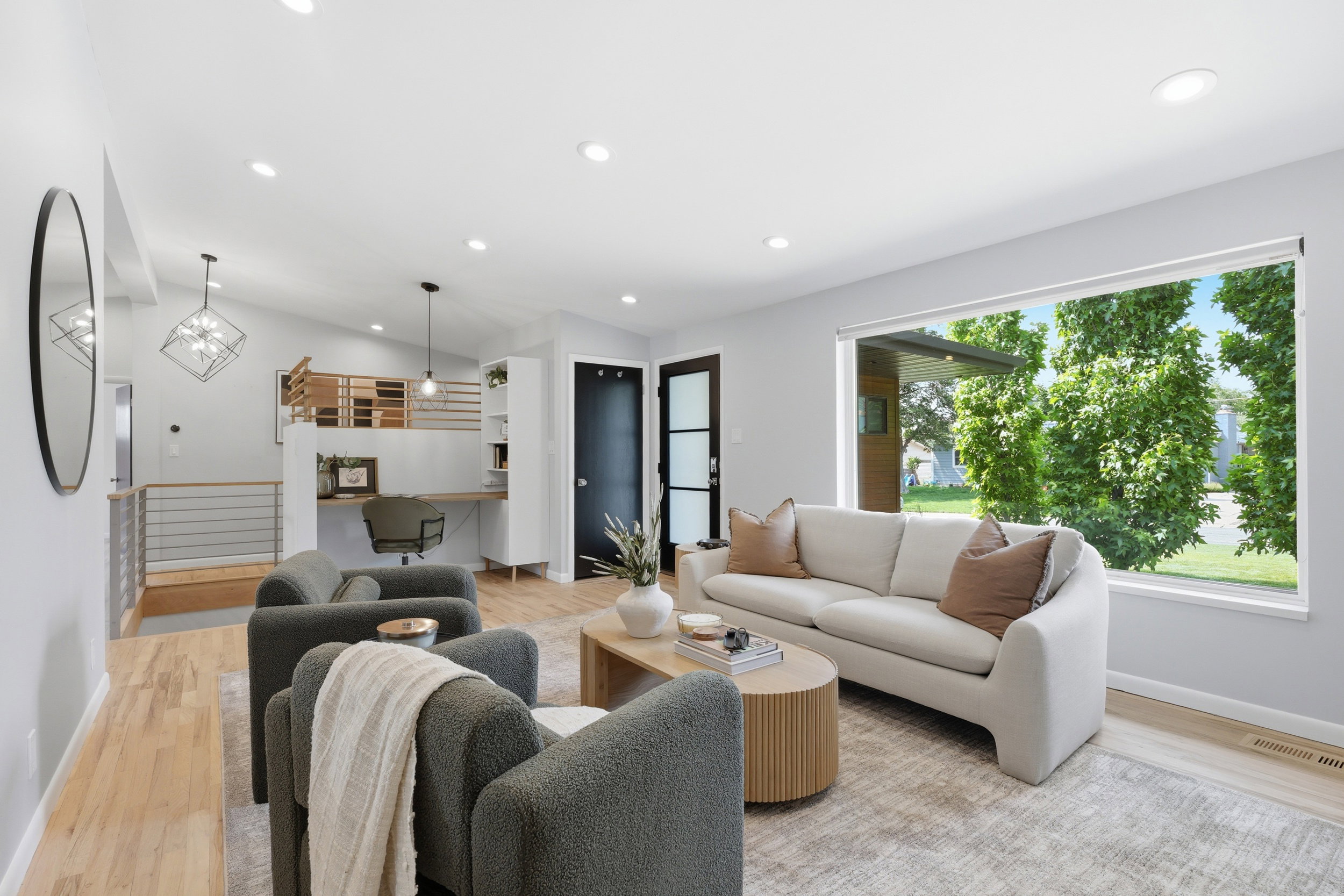 Open-concept living area featuring light wood-finish flooring, recessed lighting, and a large picture window