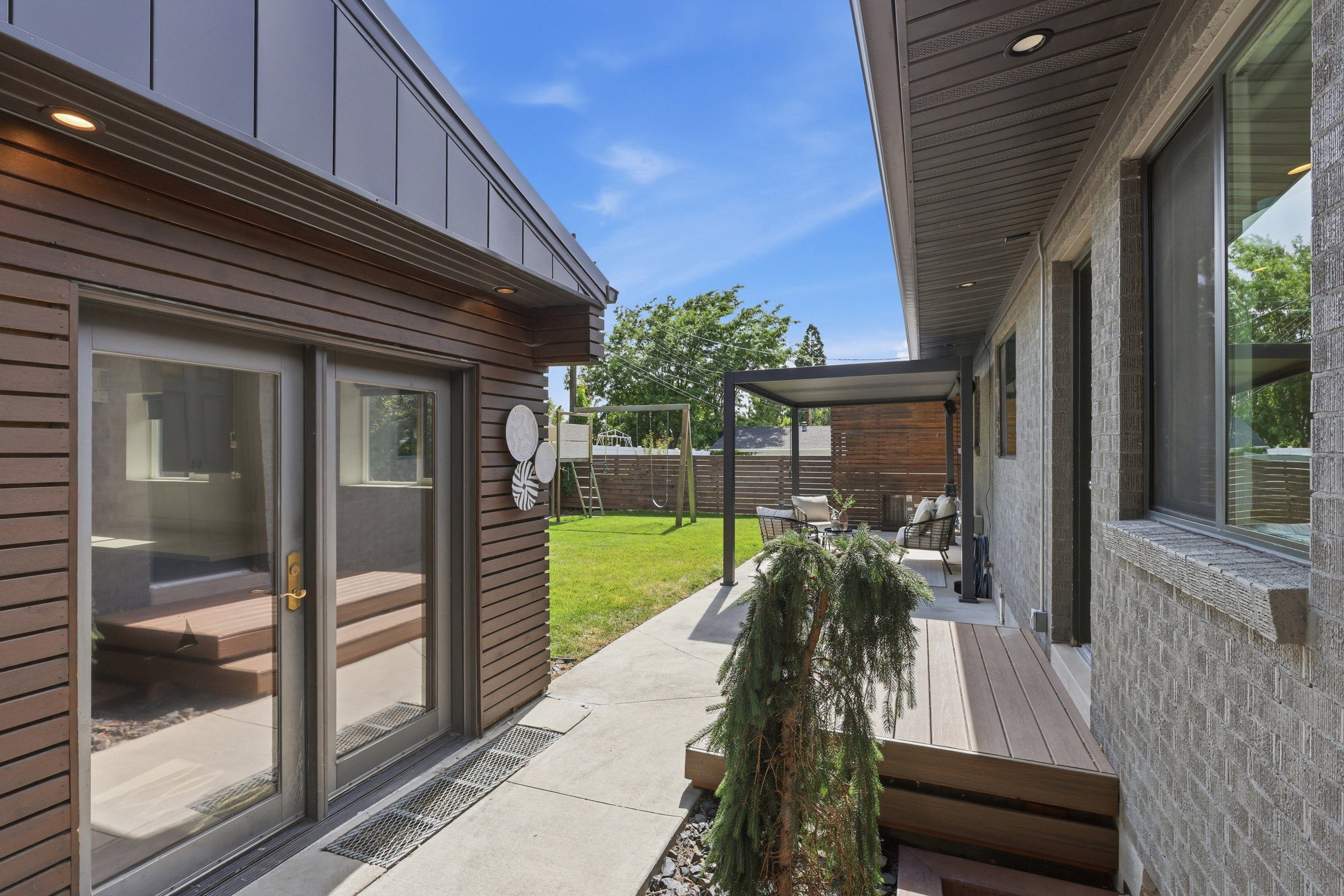 Exterior showcasing horizontal wood-finish siding, a gray metal roof, and large glass patio doors