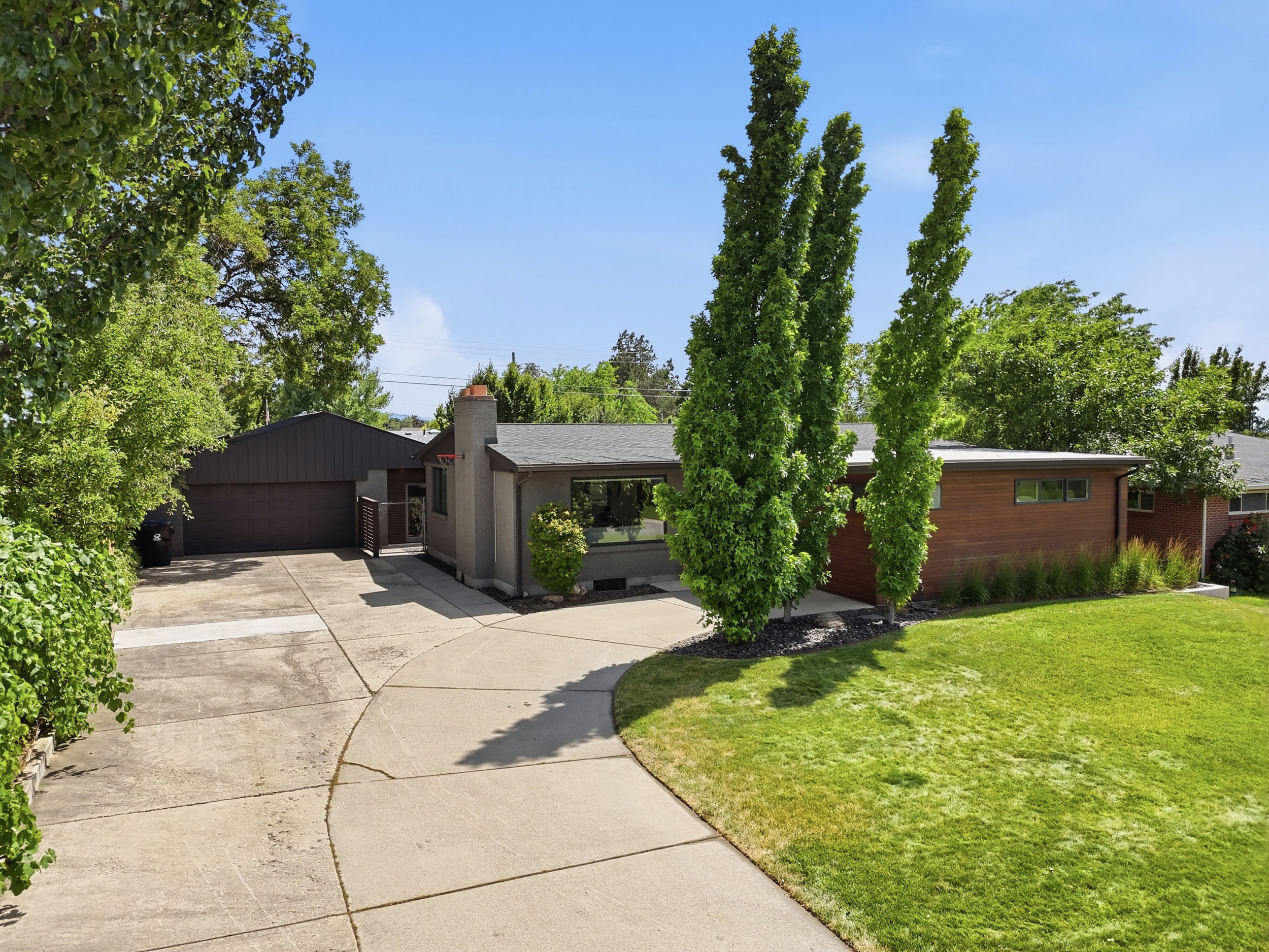 Mid-century modern residence featuring a dark gray facade with contrasting wood-panel accents