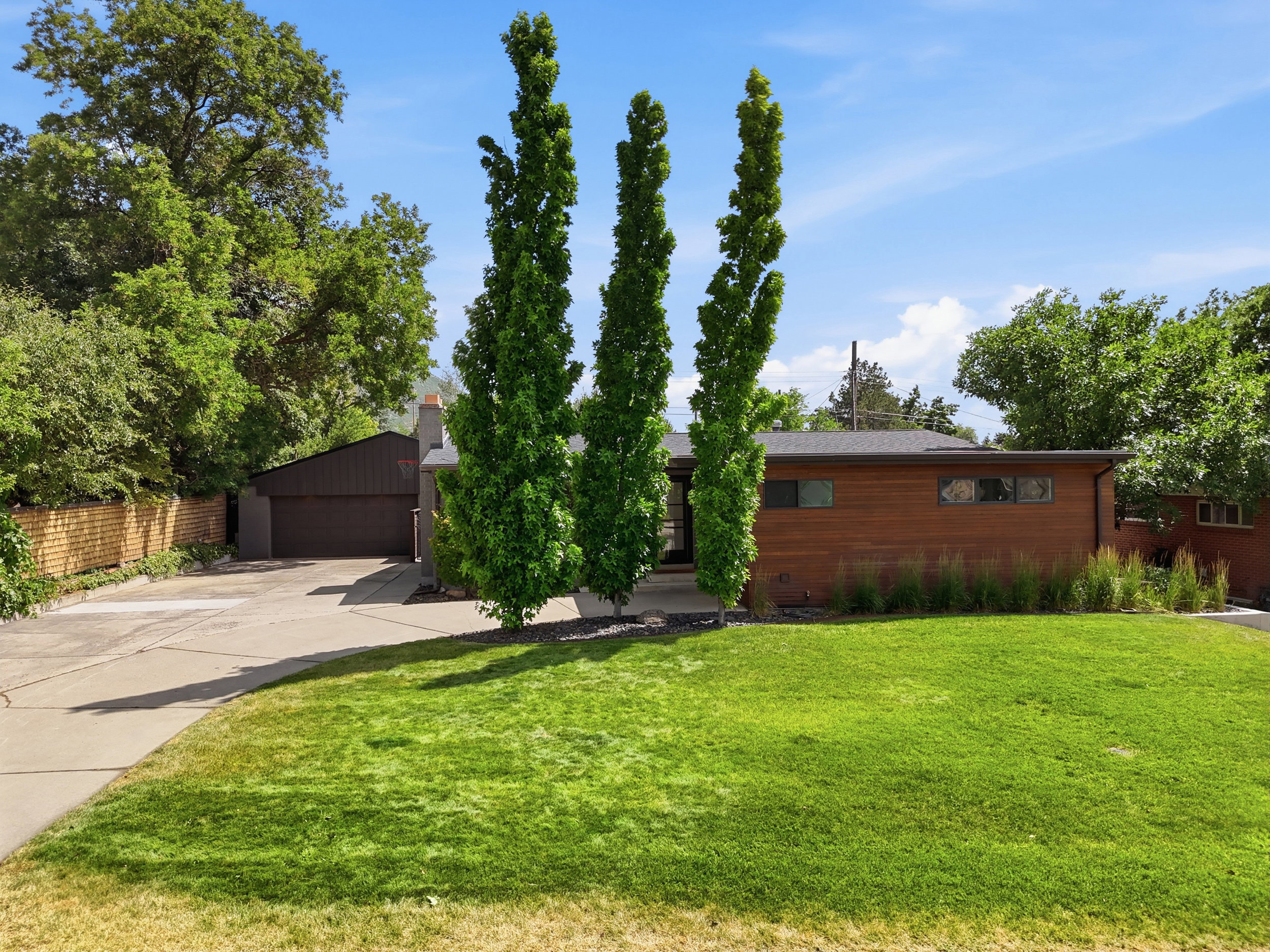 Contemporary-style residence with wood-finish siding, a dark pitched roof, and a prominent front lawn