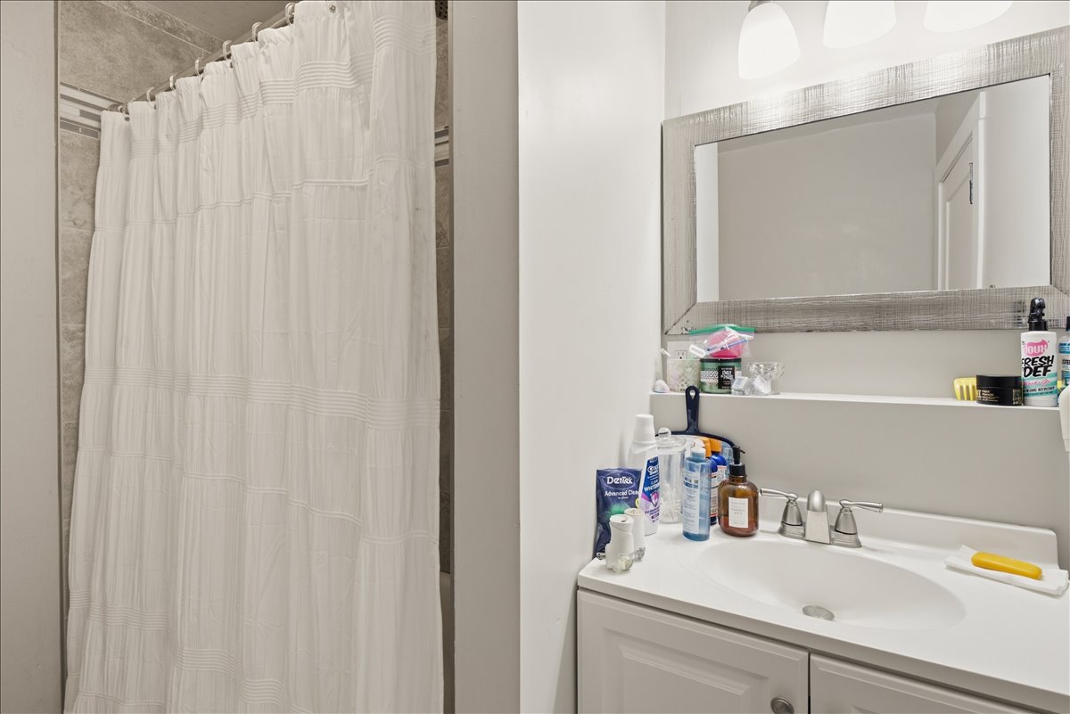 Bathroom featuring a white vanity with an integrated sink, brushed nickel faucet, and a framed mirror