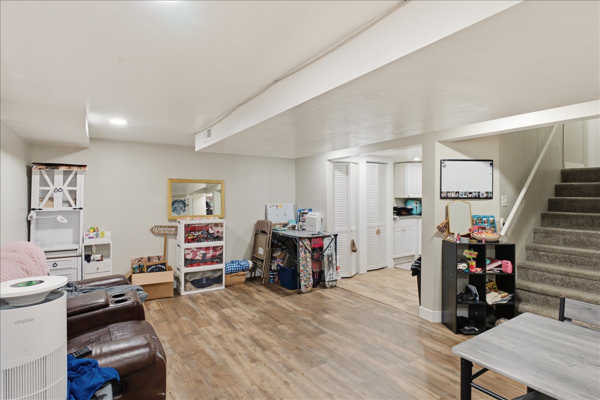Spacious interior featuring wood-finish flooring, white walls, recessed lighting, and a carpeted staircase