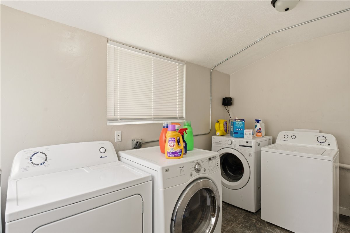 Dedicated laundry area featuring multiple appliance connections, a window with blinds, and durable flooring