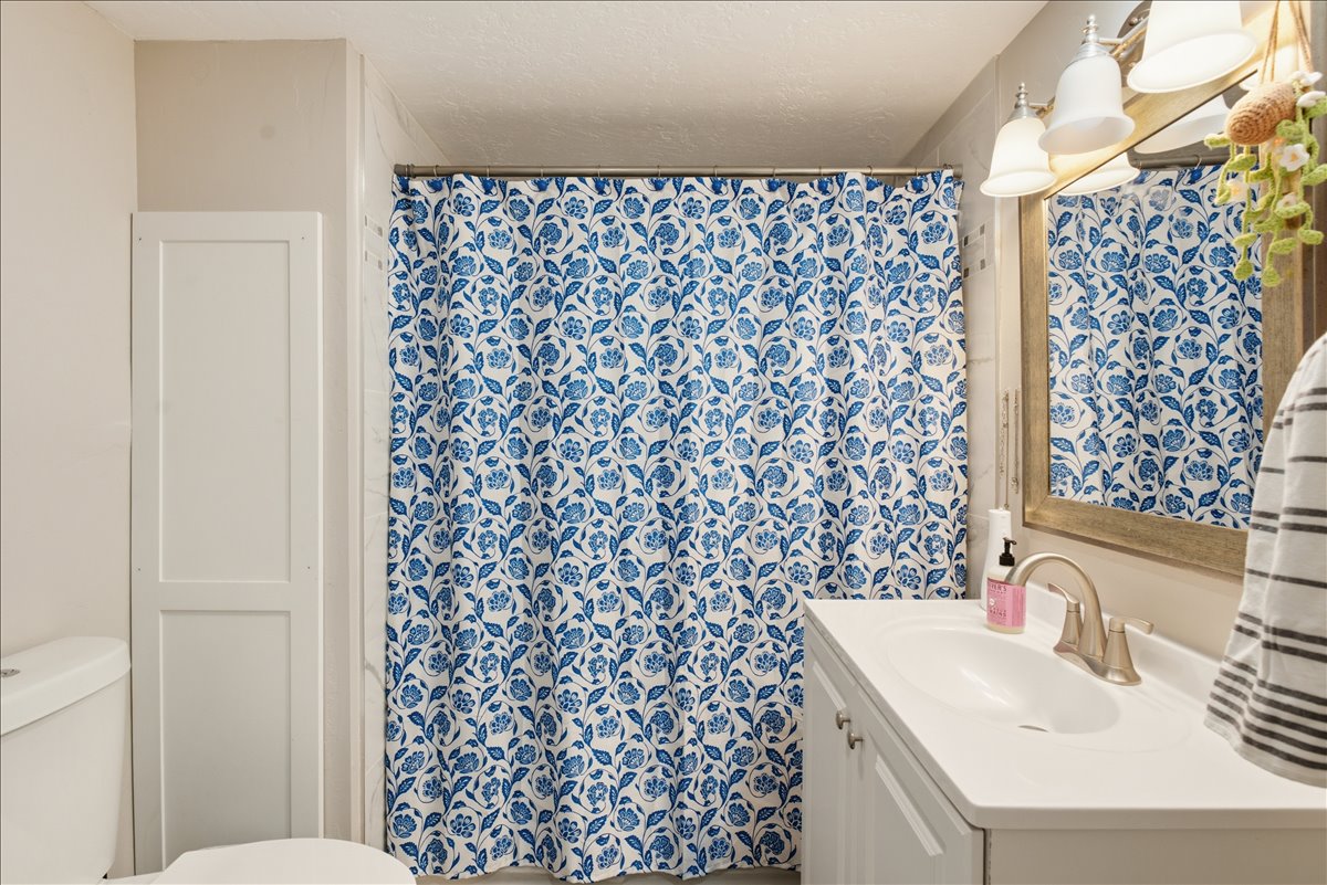 Bathroom featuring a white vanity with an integrated sink, brushed nickel faucet, and a framed mirror