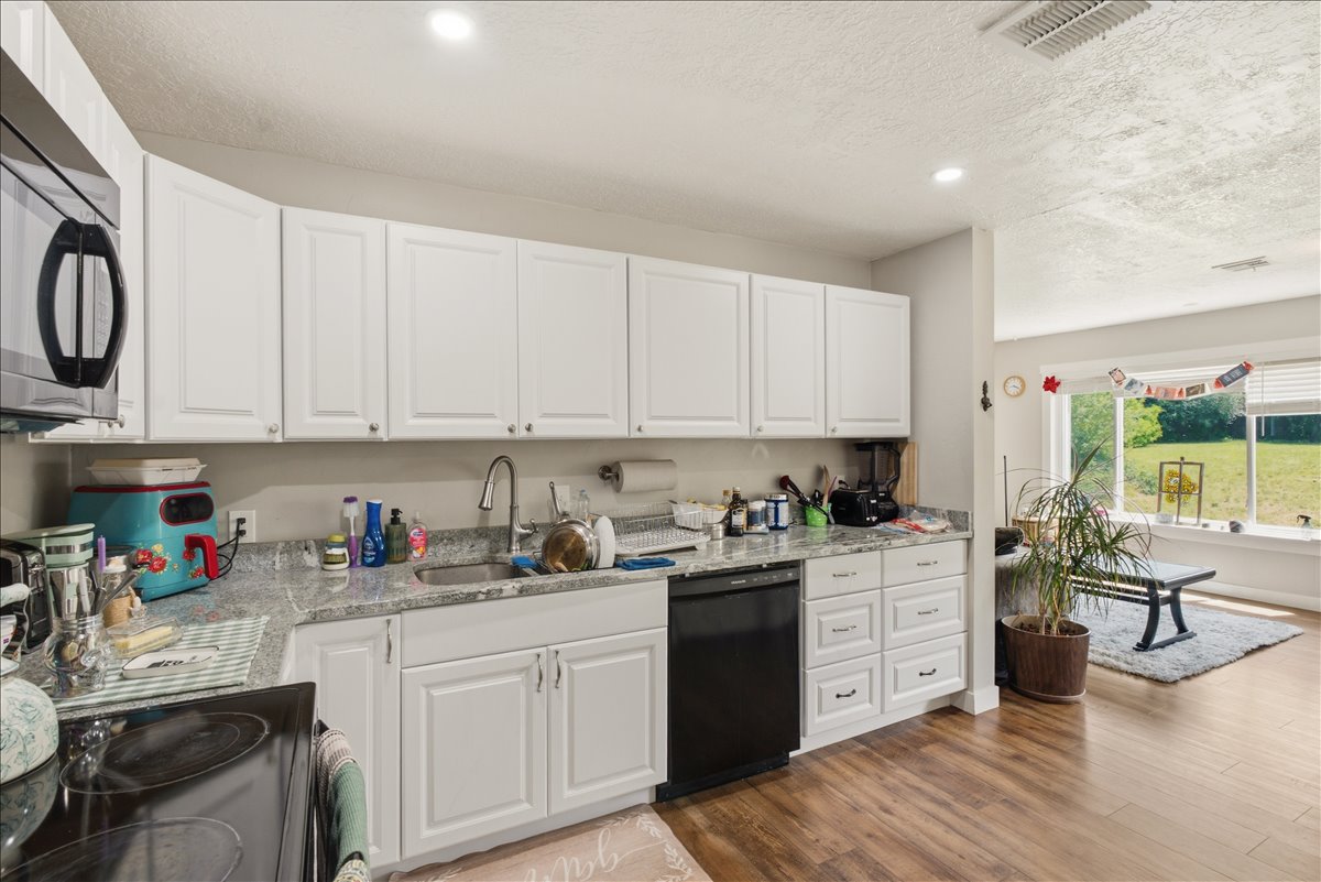 Kitchen featuring white shaker-style cabinetry, a stainless steel sink, and light-toned countertops