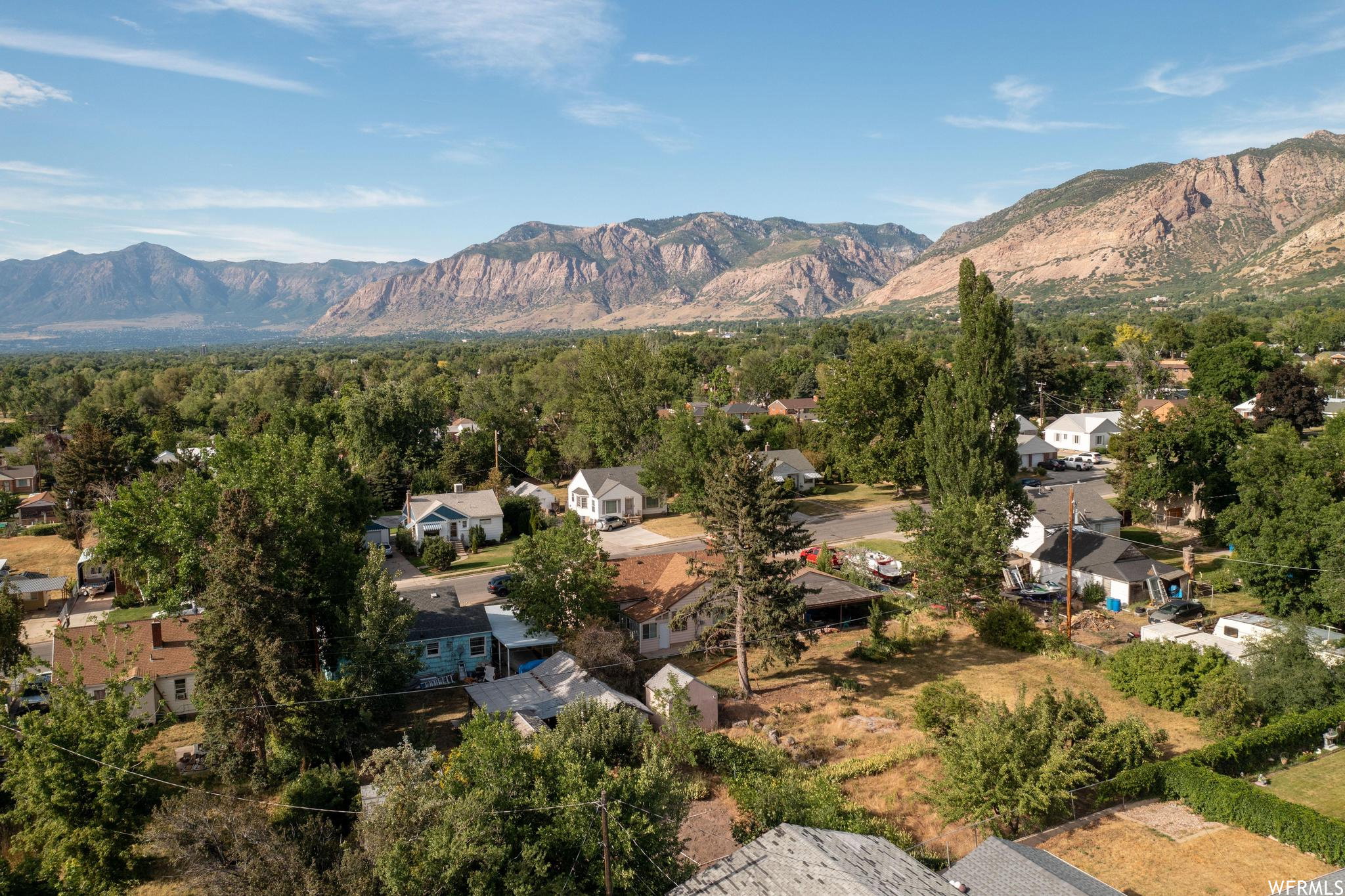 Expansive aerial perspective showcasing a residential neighborhood with distant mountain ranges and a large body of water