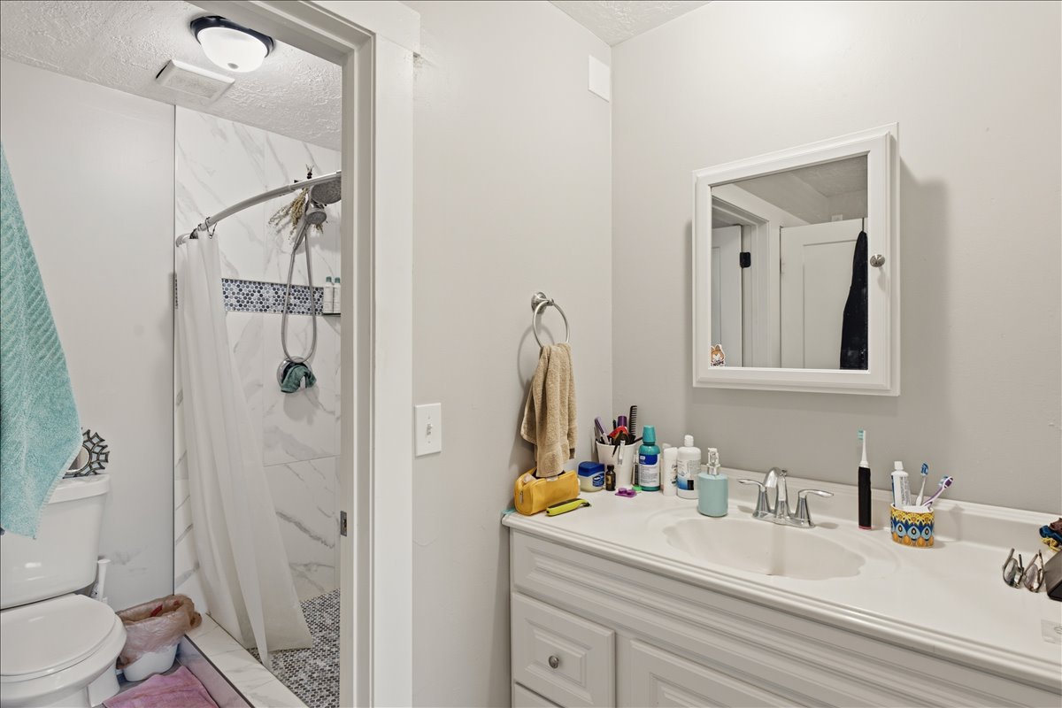 Bathroom featuring a vanity with an integrated sink, built-in medicine cabinet, and a tiled shower with mosaic accent band