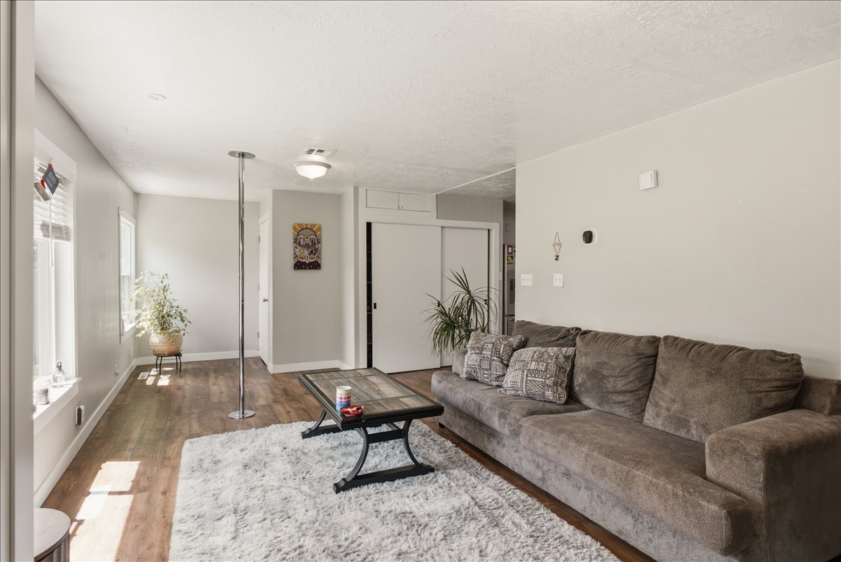 Living area with wood-finish flooring, light grey wall paint, and white trim