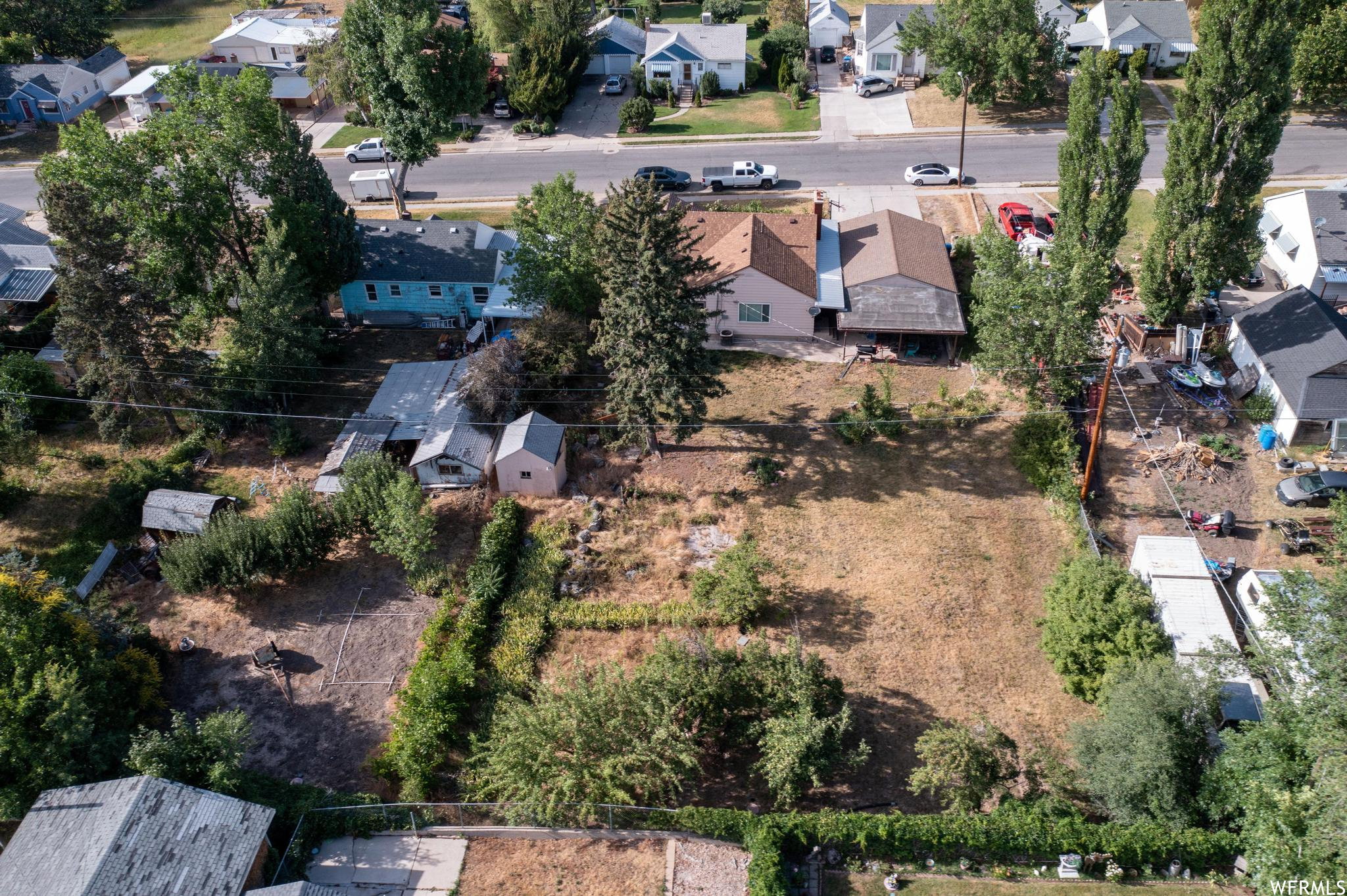 Expansive undeveloped lot with perimeter landscaping, featuring established trees and shrubs