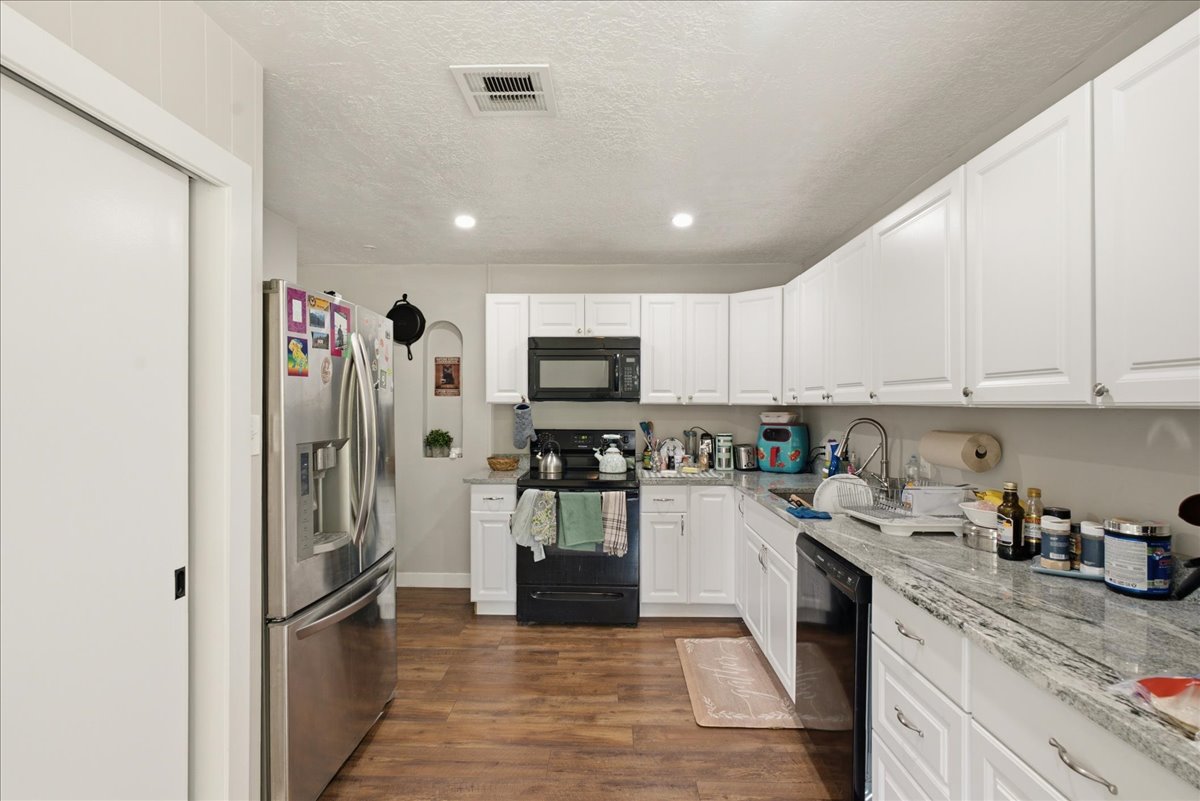 Kitchen featuring wood-finish flooring, white cabinetry, and light-colored countertops