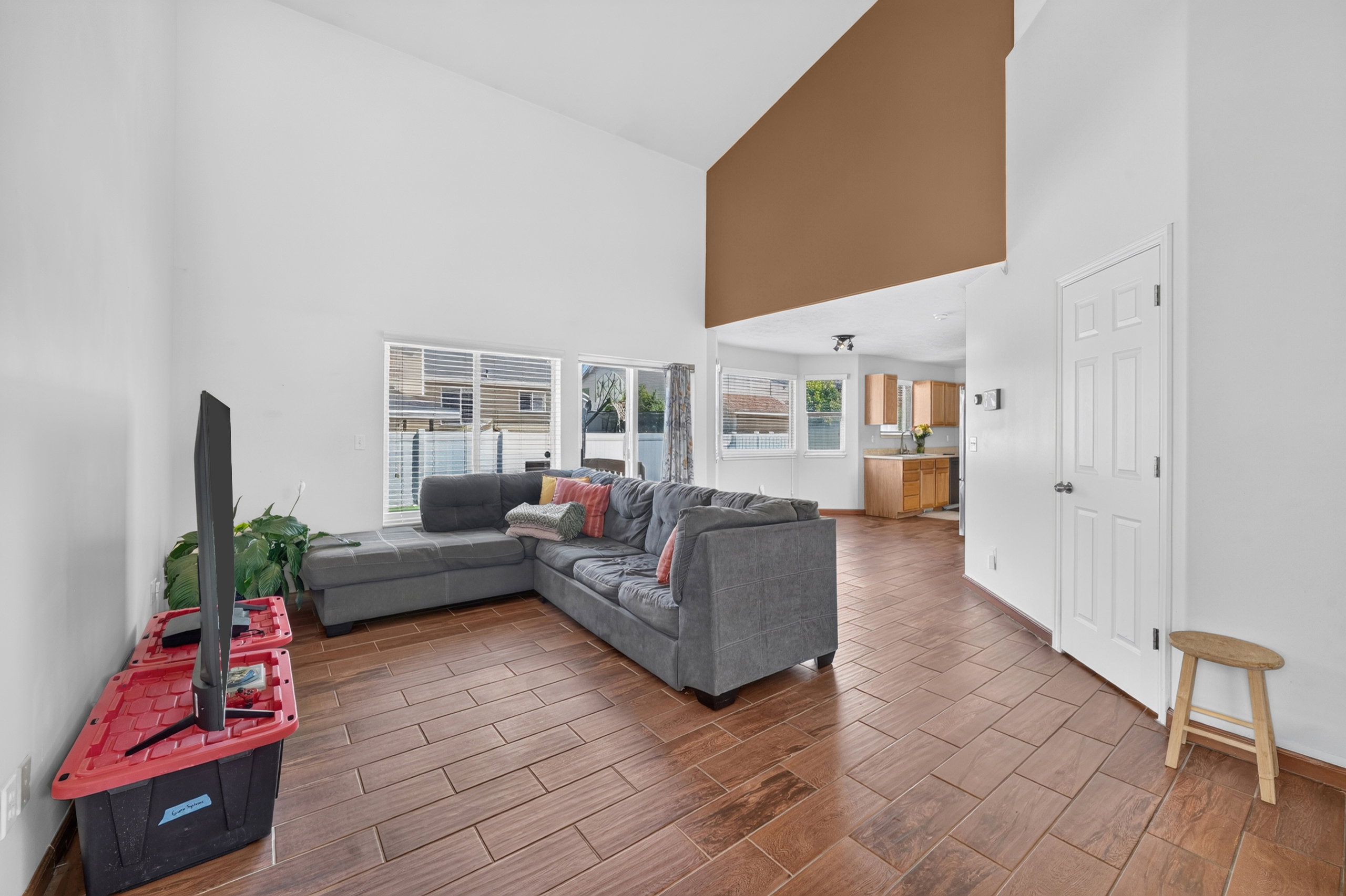 Living area featuring soaring vaulted ceilings, a prominent accent wall, and wood-look tile flooring