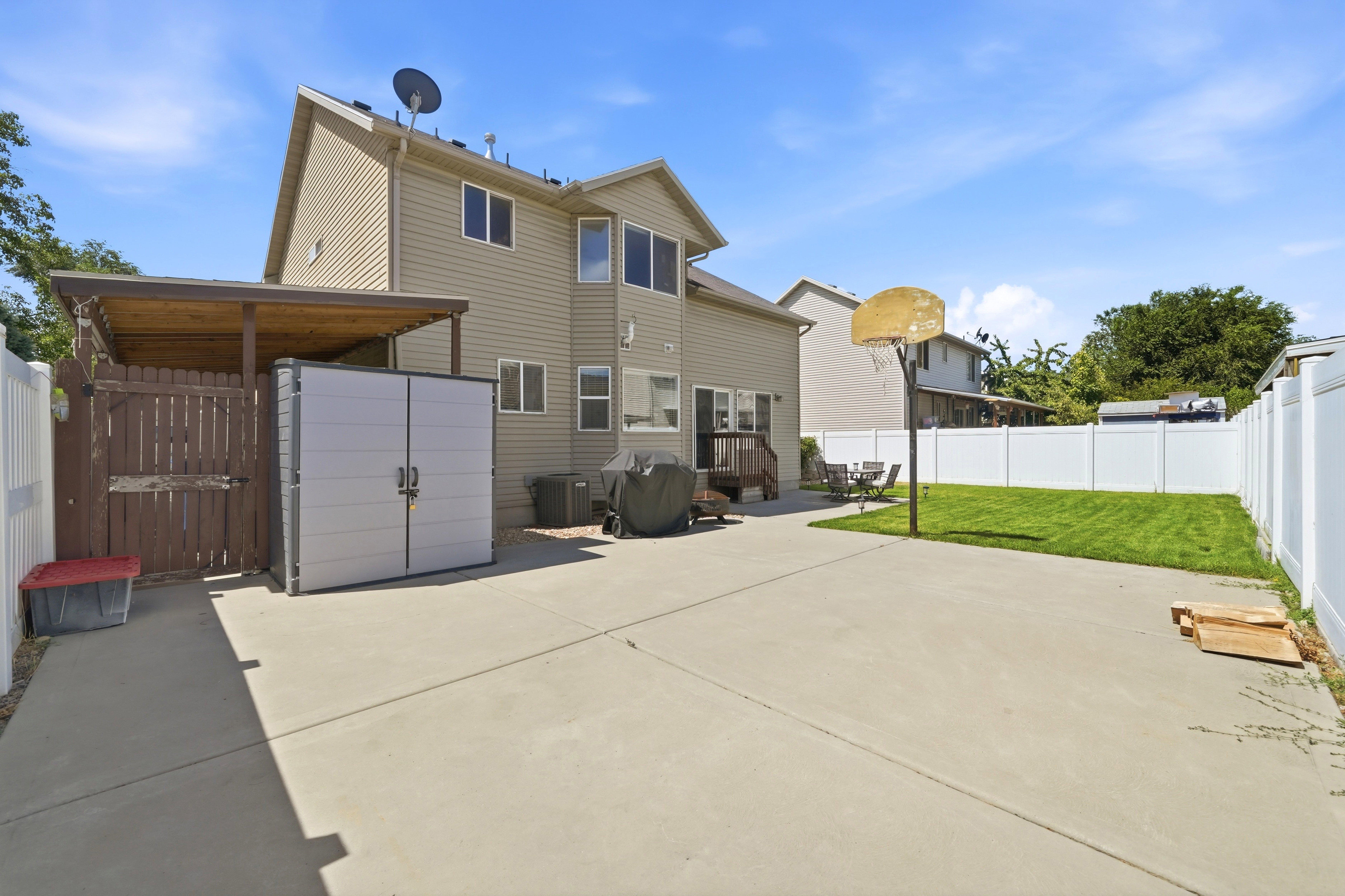 Expansive concrete patio with a covered pergola and attached storage shed