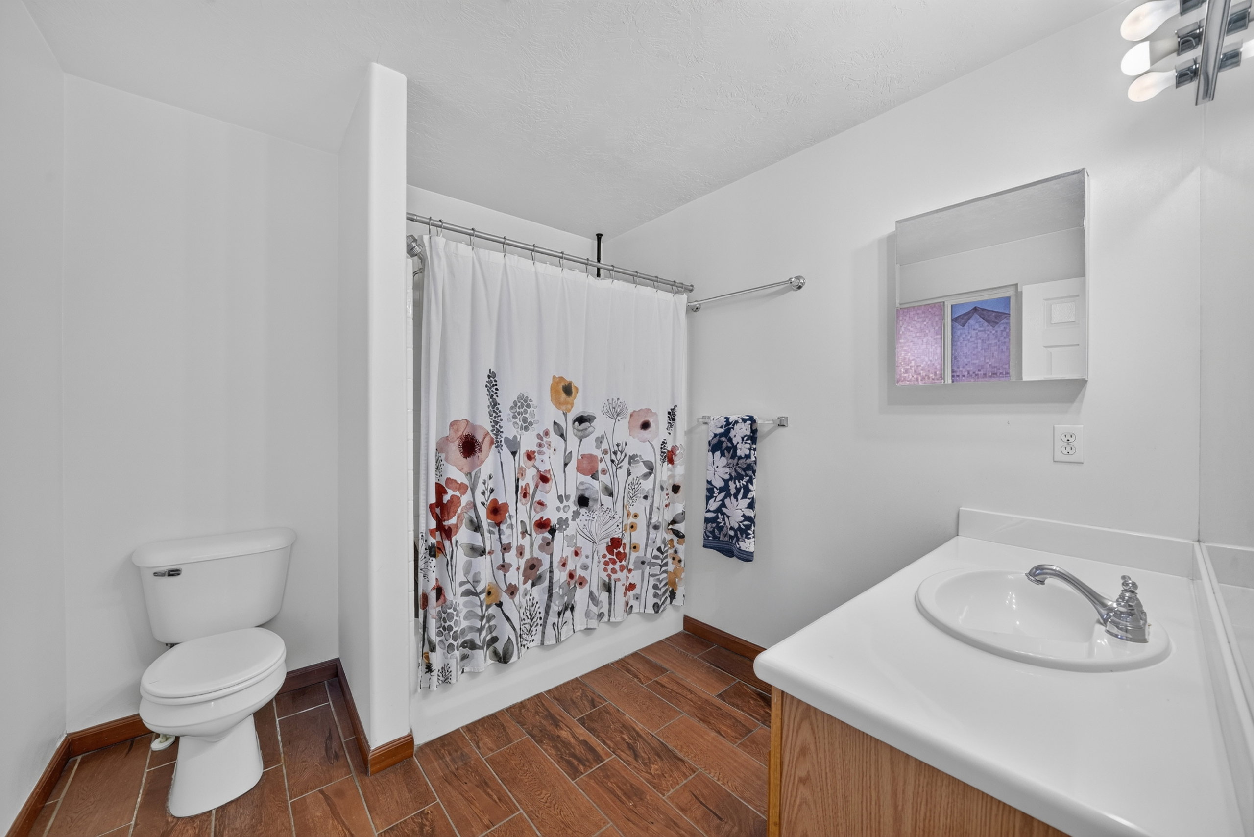 Bathroom featuring a single vanity with an integrated sink, wood-finish flooring, and a shower/tub combination