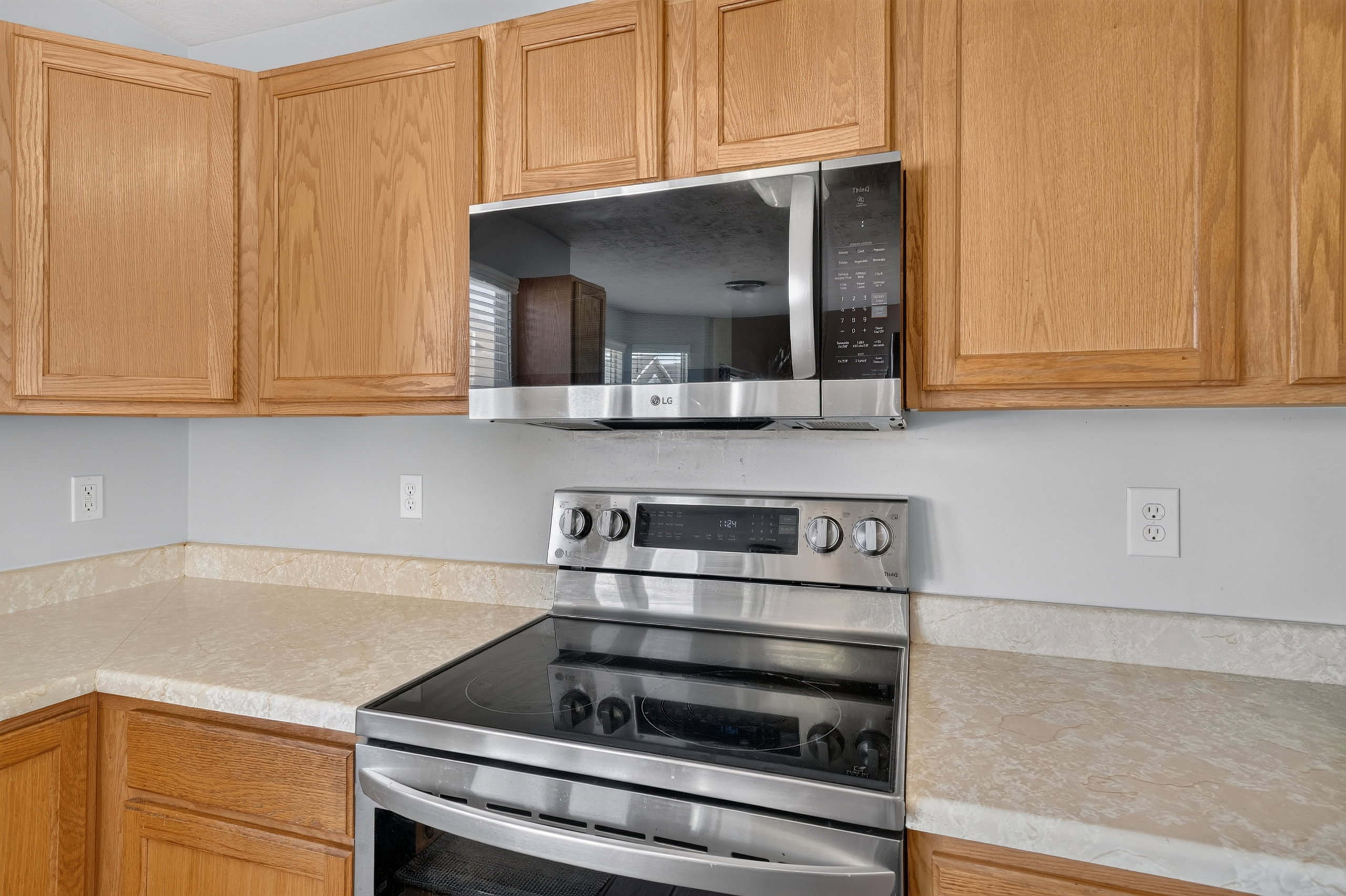 Kitchen featuring wood-finish cabinetry, light-toned countertops, stainless steel range, and an over-the-range microwave