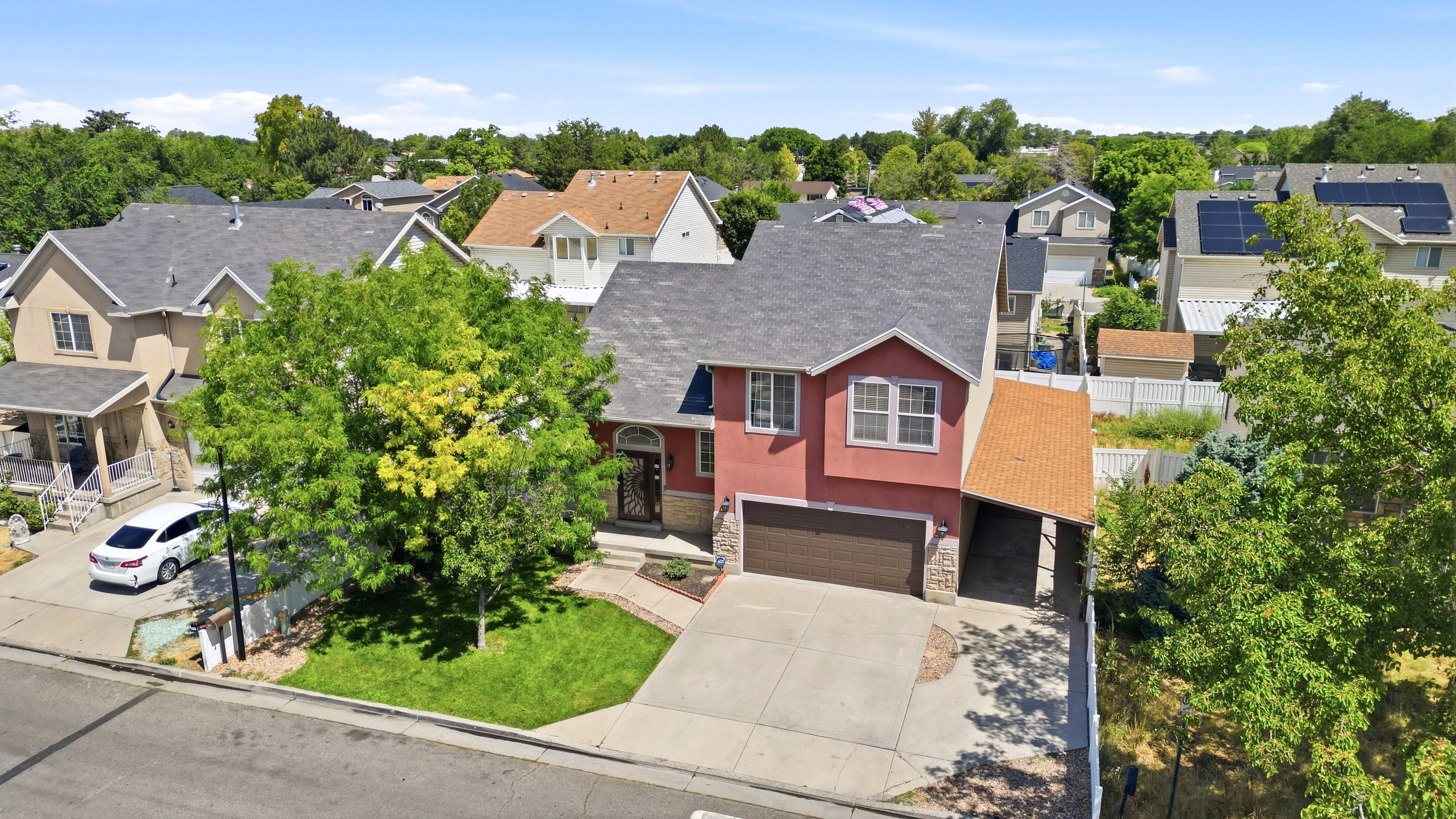 Two-story residence featuring a red stucco exterior, an attached two-car garage, and a covered side carport