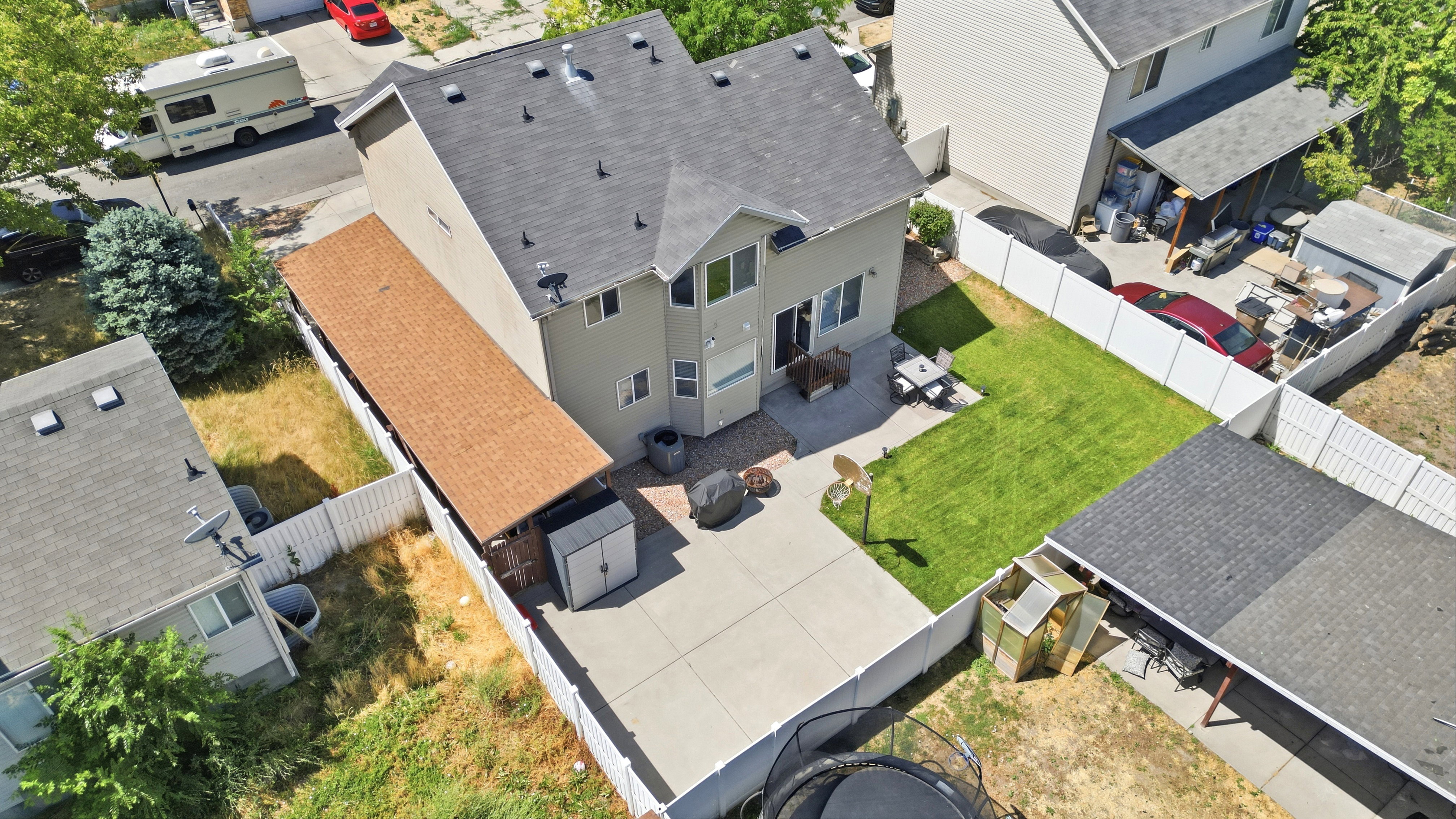 Rear exterior featuring a concrete patio, a green lawn, and a light-colored privacy fence