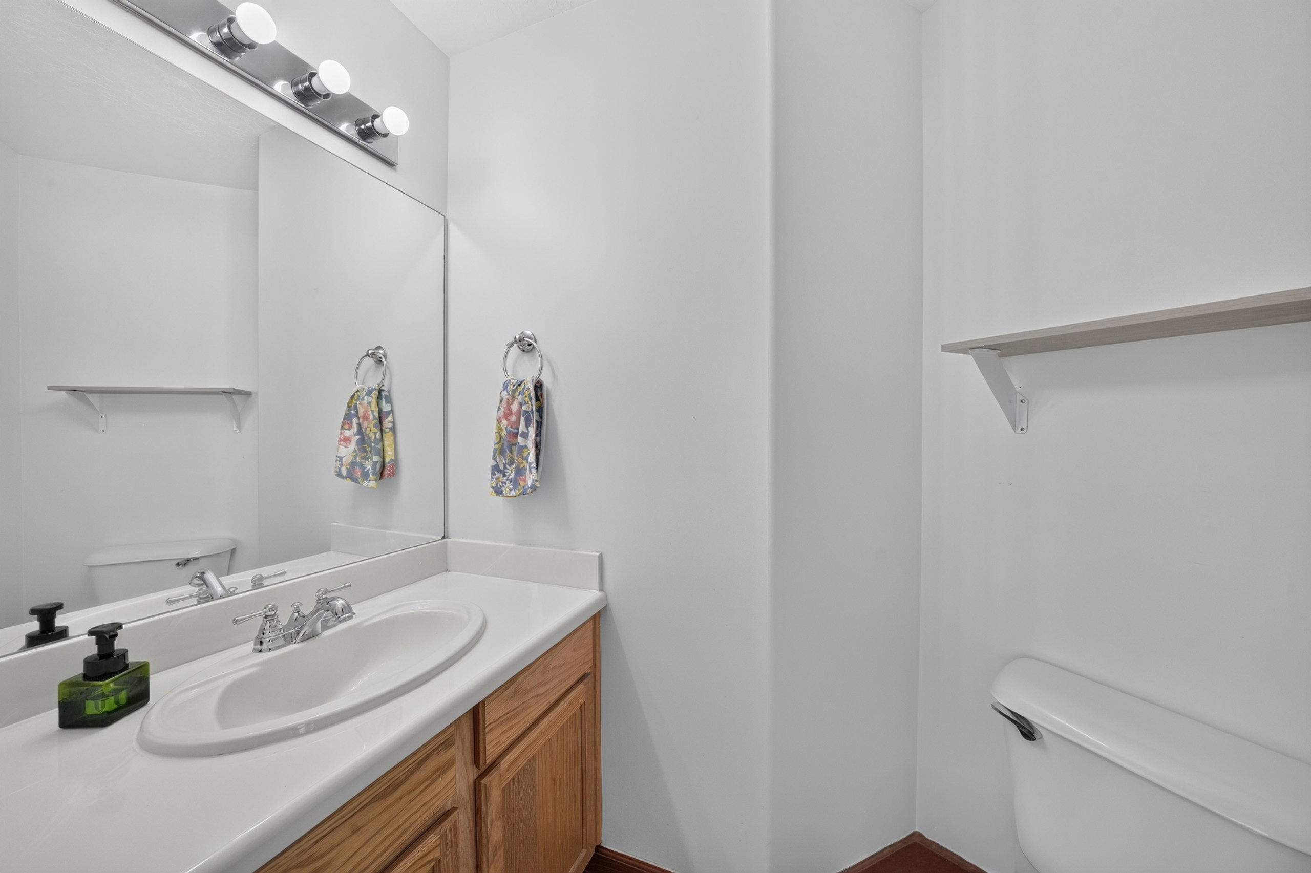 Bathroom vanity featuring a white countertop with an integrated sink, wood-finish cabinetry, and a mirrored wall