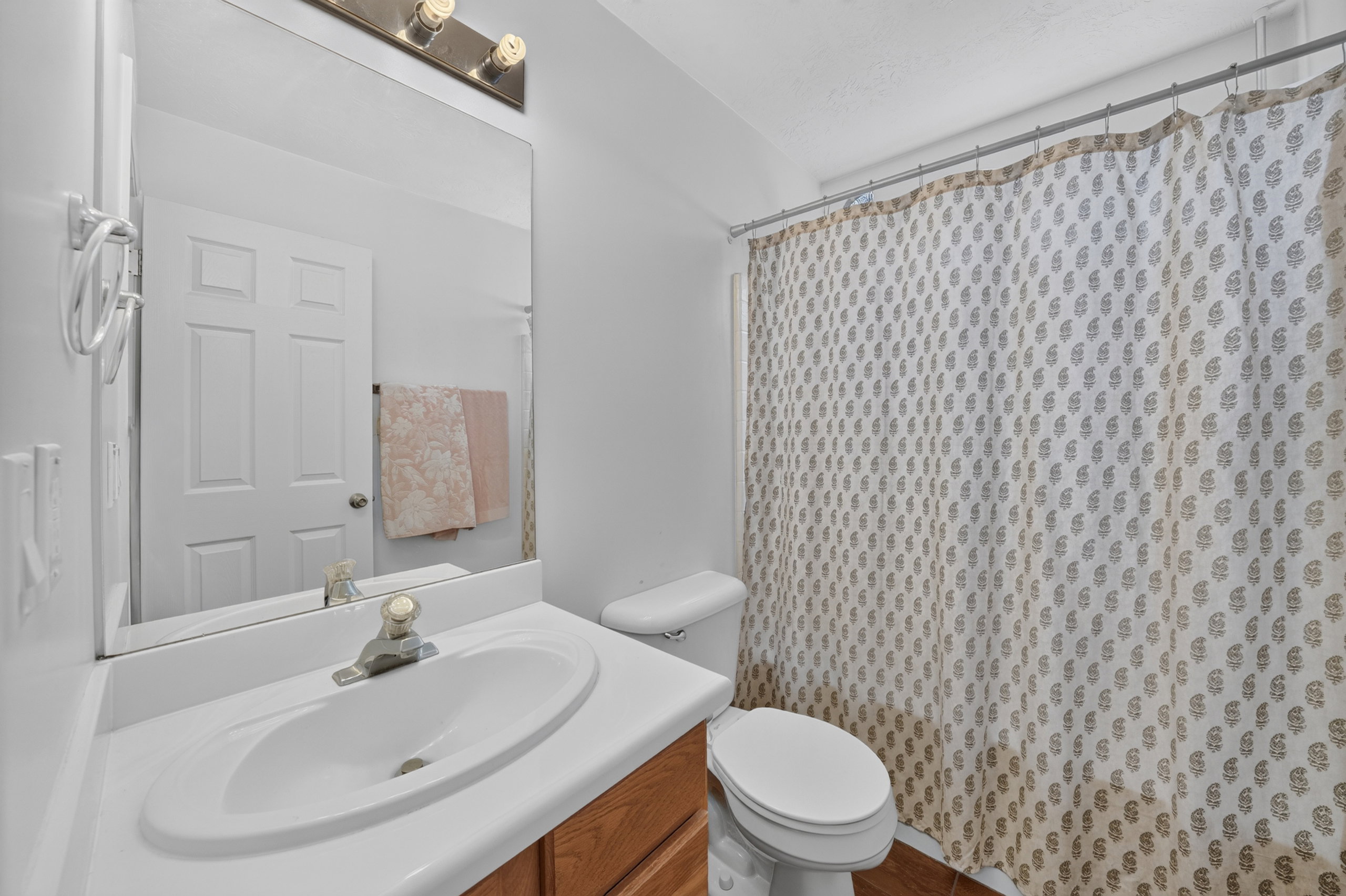 Bathroom featuring a single vanity with a laminate countertop, an oval undermount sink, and a wood-finish cabinet