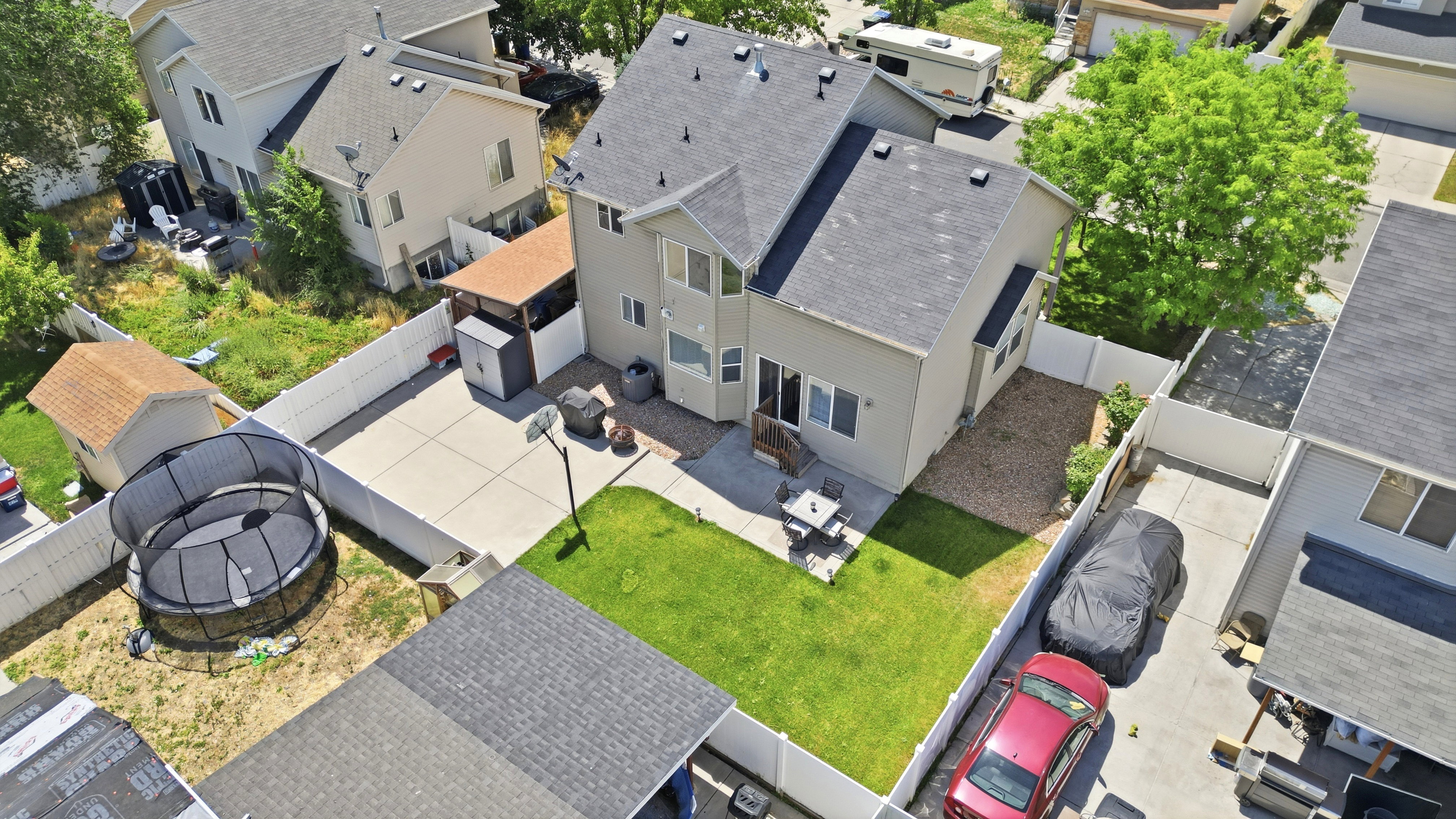 Rear exterior featuring a two-story design, attached patio, expansive fenced yard, and an additional shed