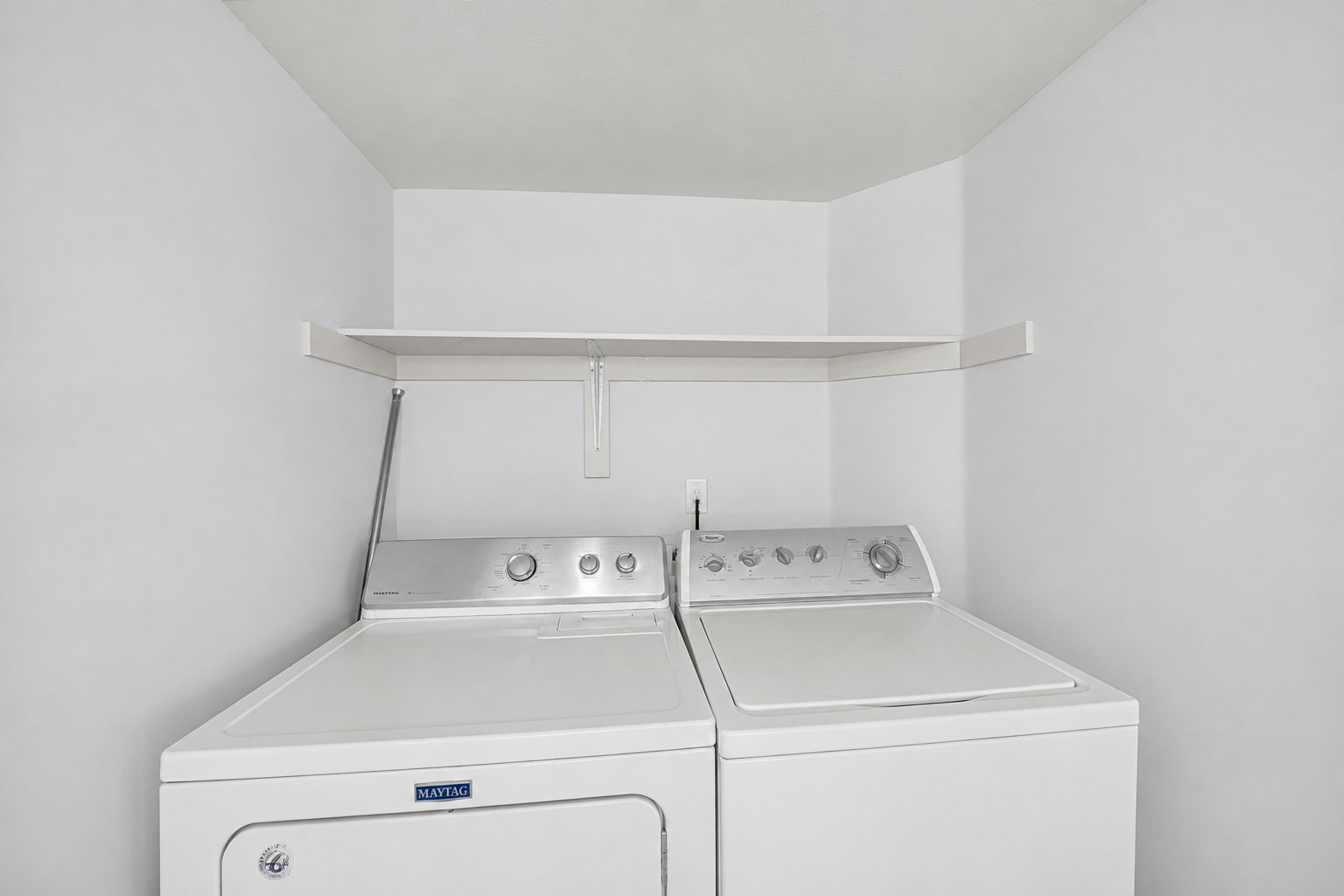 Dedicated laundry area featuring a white top-load washing machine and dryer set with a white storage shelf above