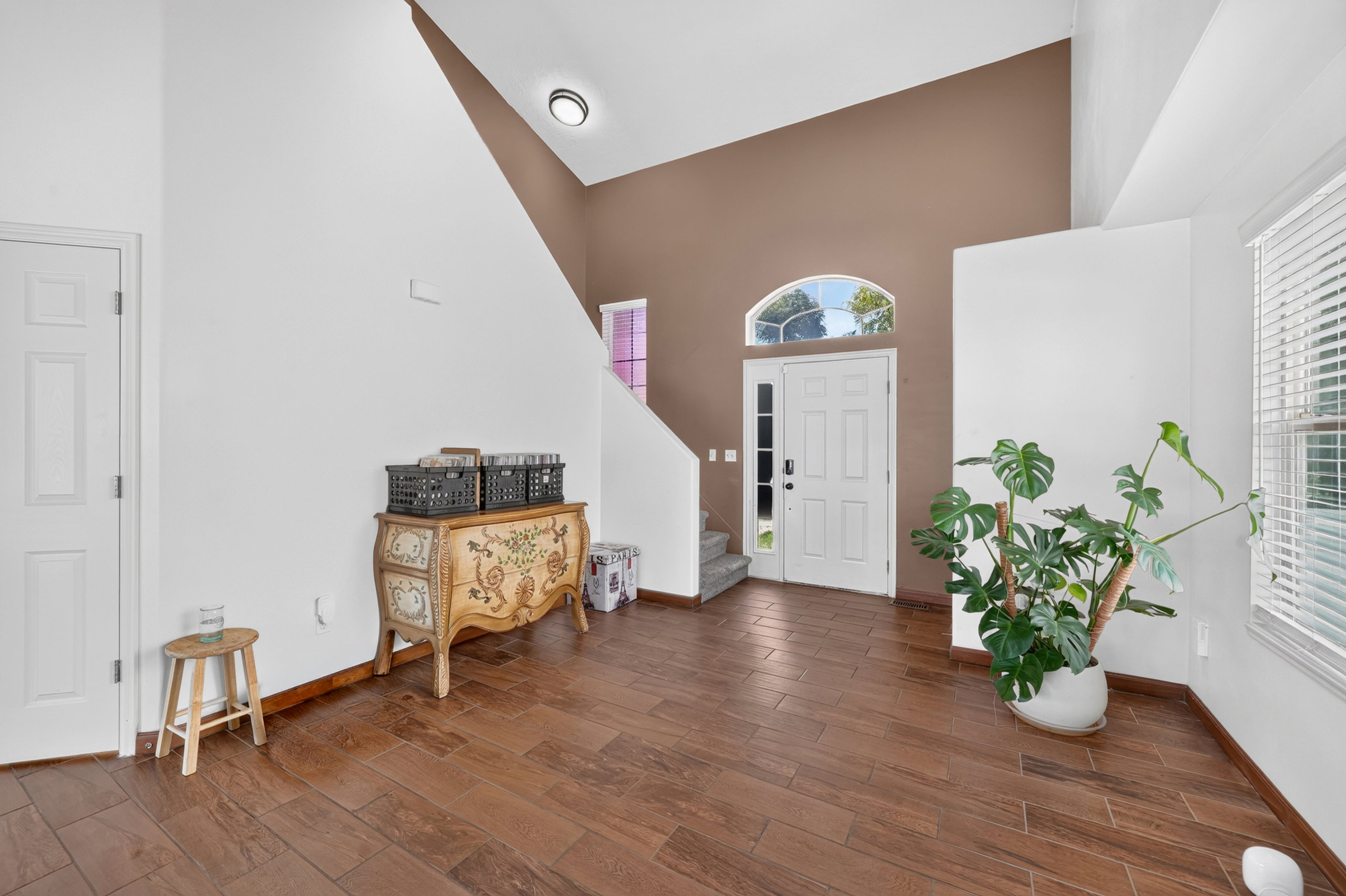 Entryway featuring wood-finish flooring, a white paneled entry door with an arched transom, and vaulted ceilings with a recessed light fixture