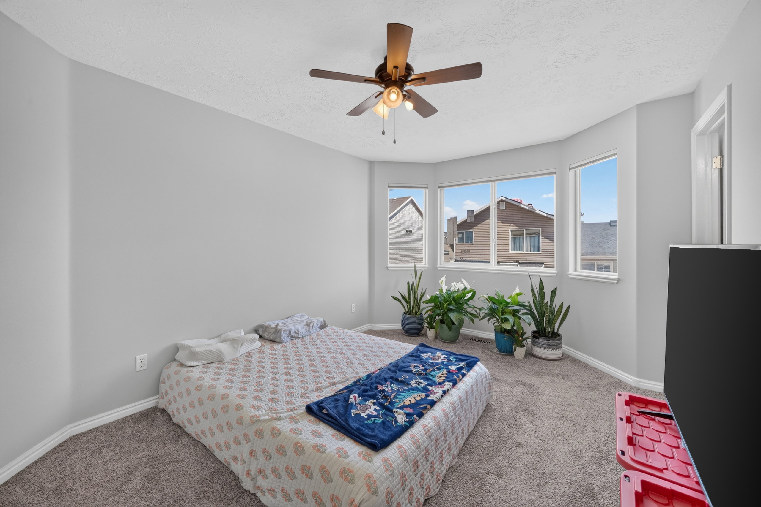 Bay window framing exterior surroundings, complemented by a ceiling fan with integrated lighting