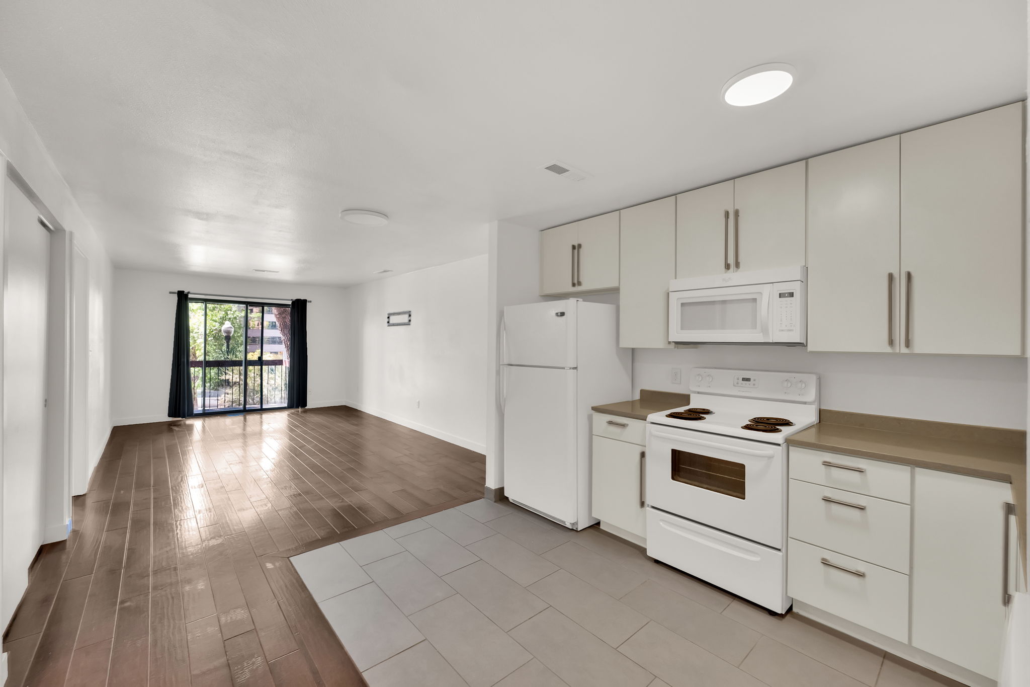 Kitchen featuring white cabinetry, integrated microwave, white electric range, and light-toned countertops