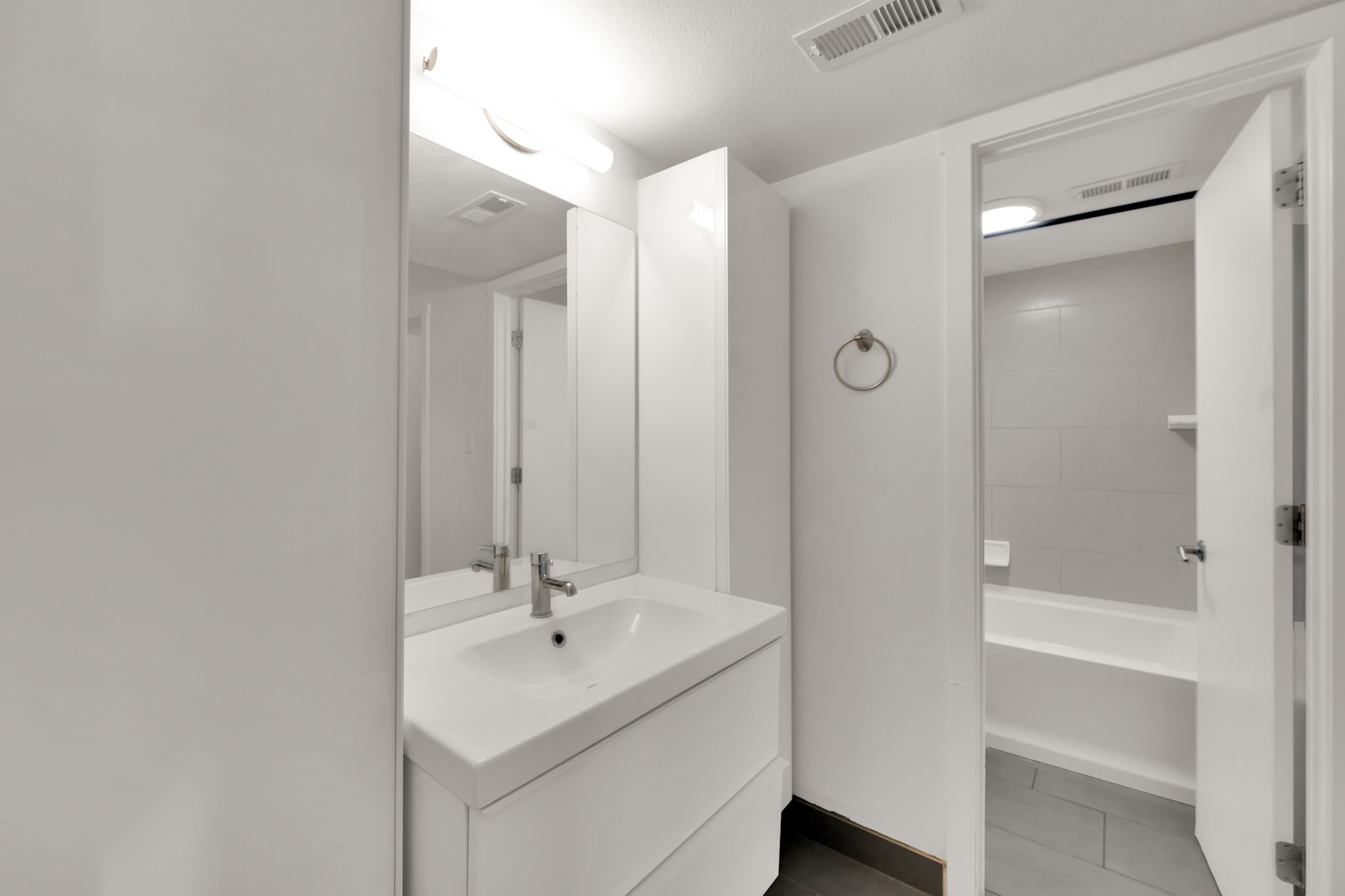 Bathroom featuring a white vanity with integrated sink, chrome faucet, and mirrored medicine cabinet
