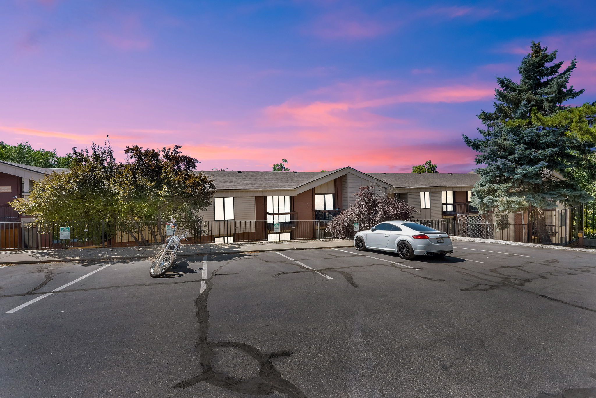 Multi-unit property featuring a neutral exterior, ample parking, and mature landscaping