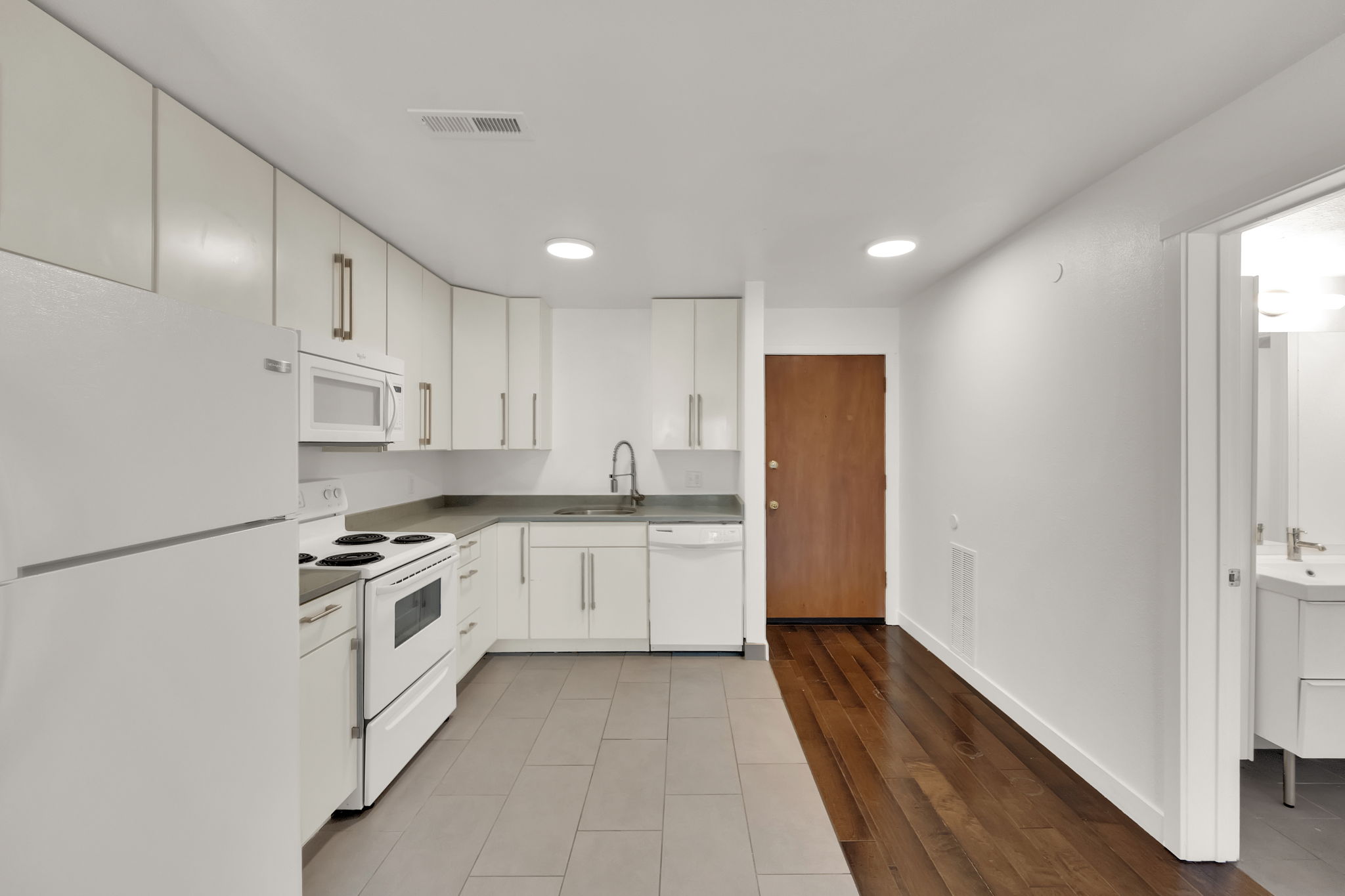 Kitchen featuring white cabinetry, white appliances, dark countertops, and a tile backsplash