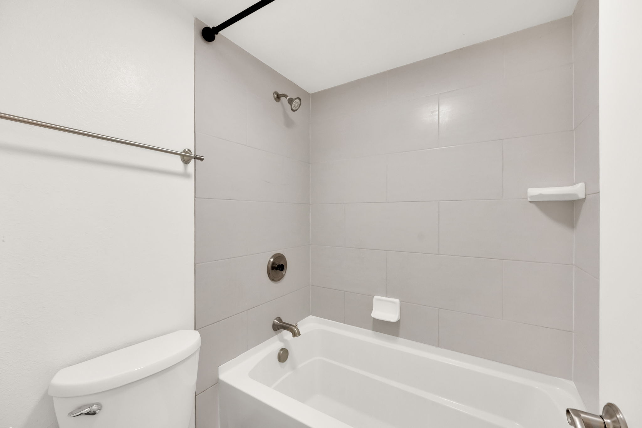 Bathtub and shower combination featuring large format tile surround