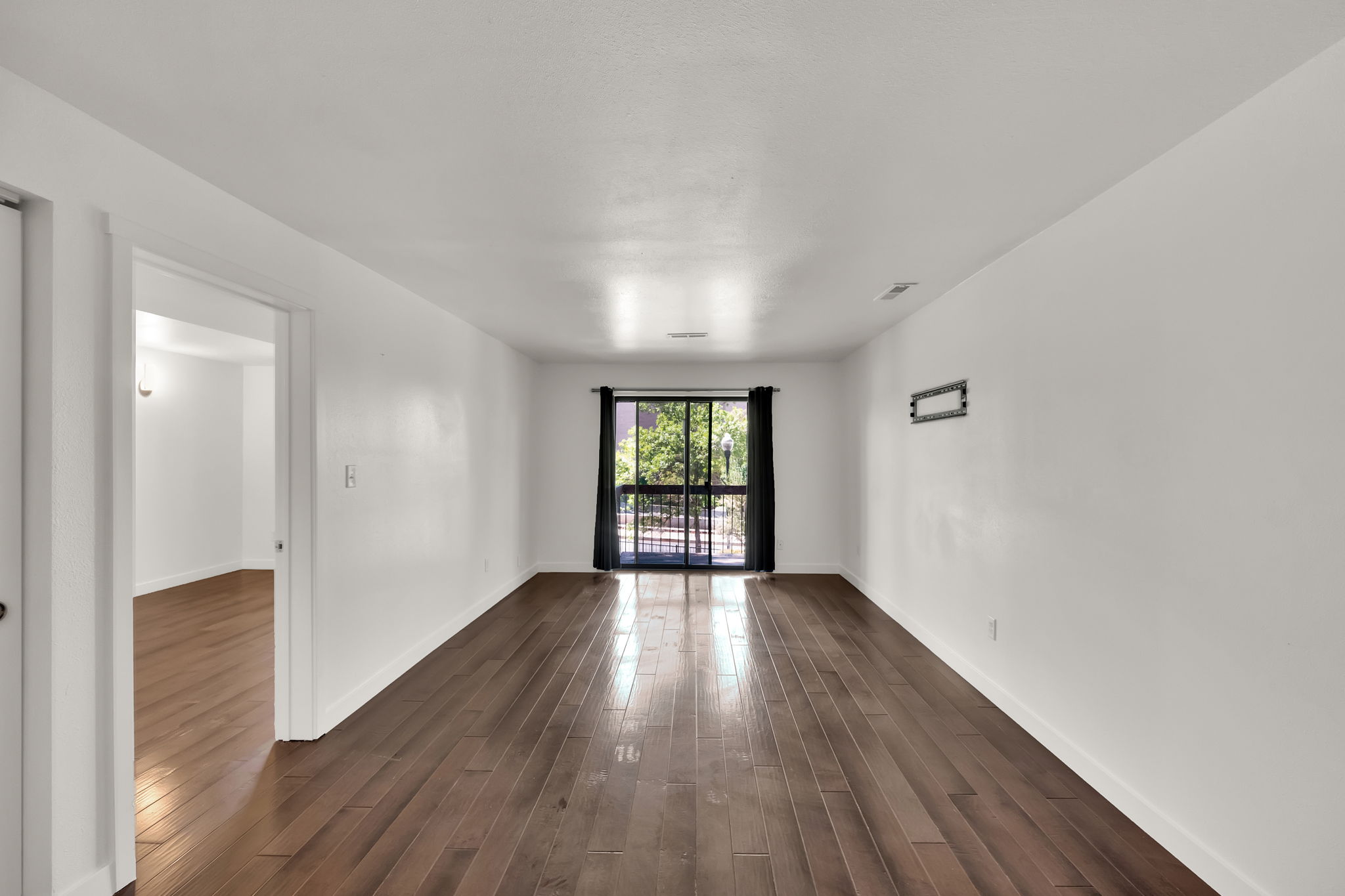 Spacious room featuring wood-finish flooring and white walls