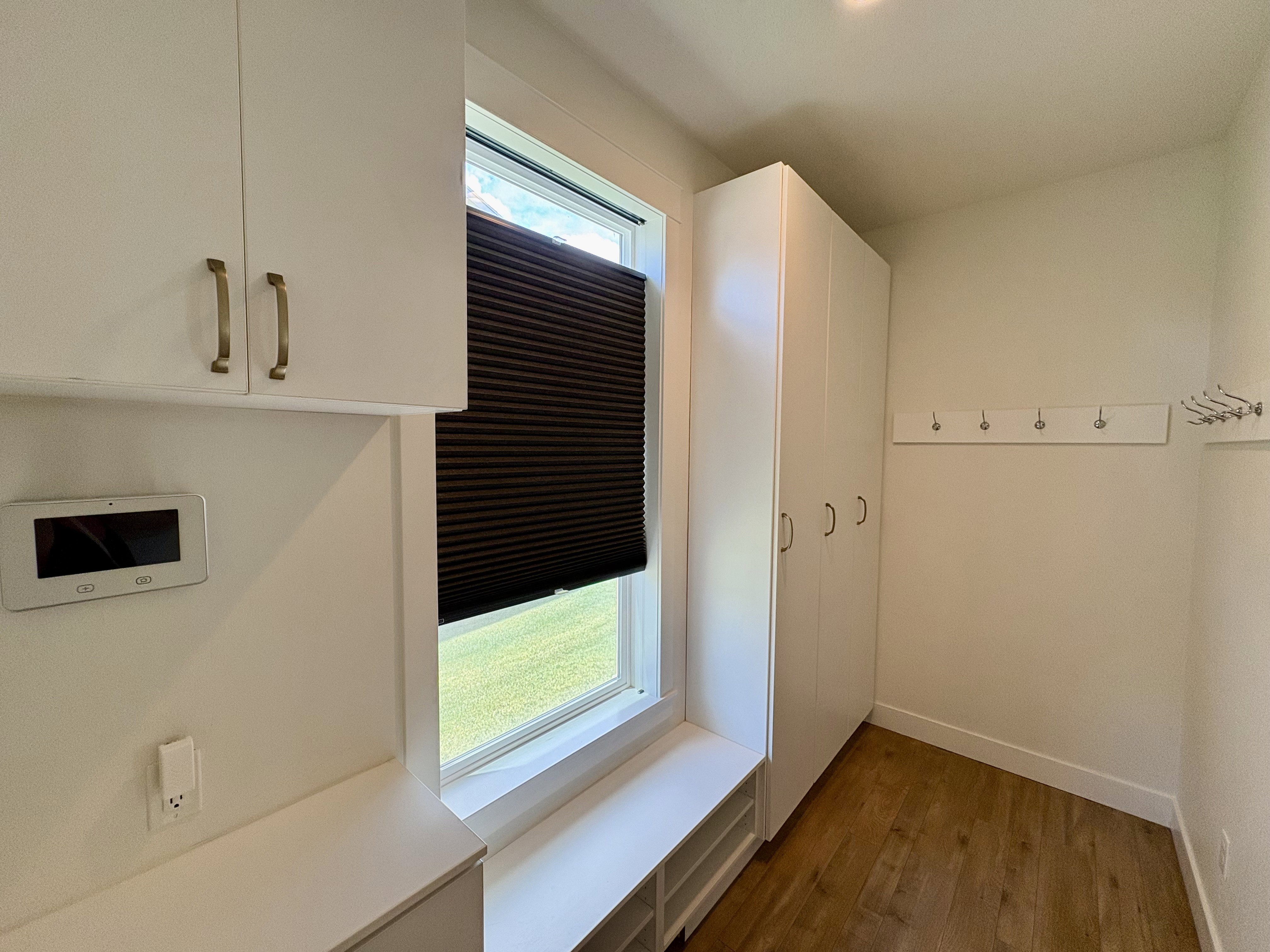Entryway featuring built-in white cabinetry, integrated storage bench, wall-mounted coat hooks, and wood-finish flooring