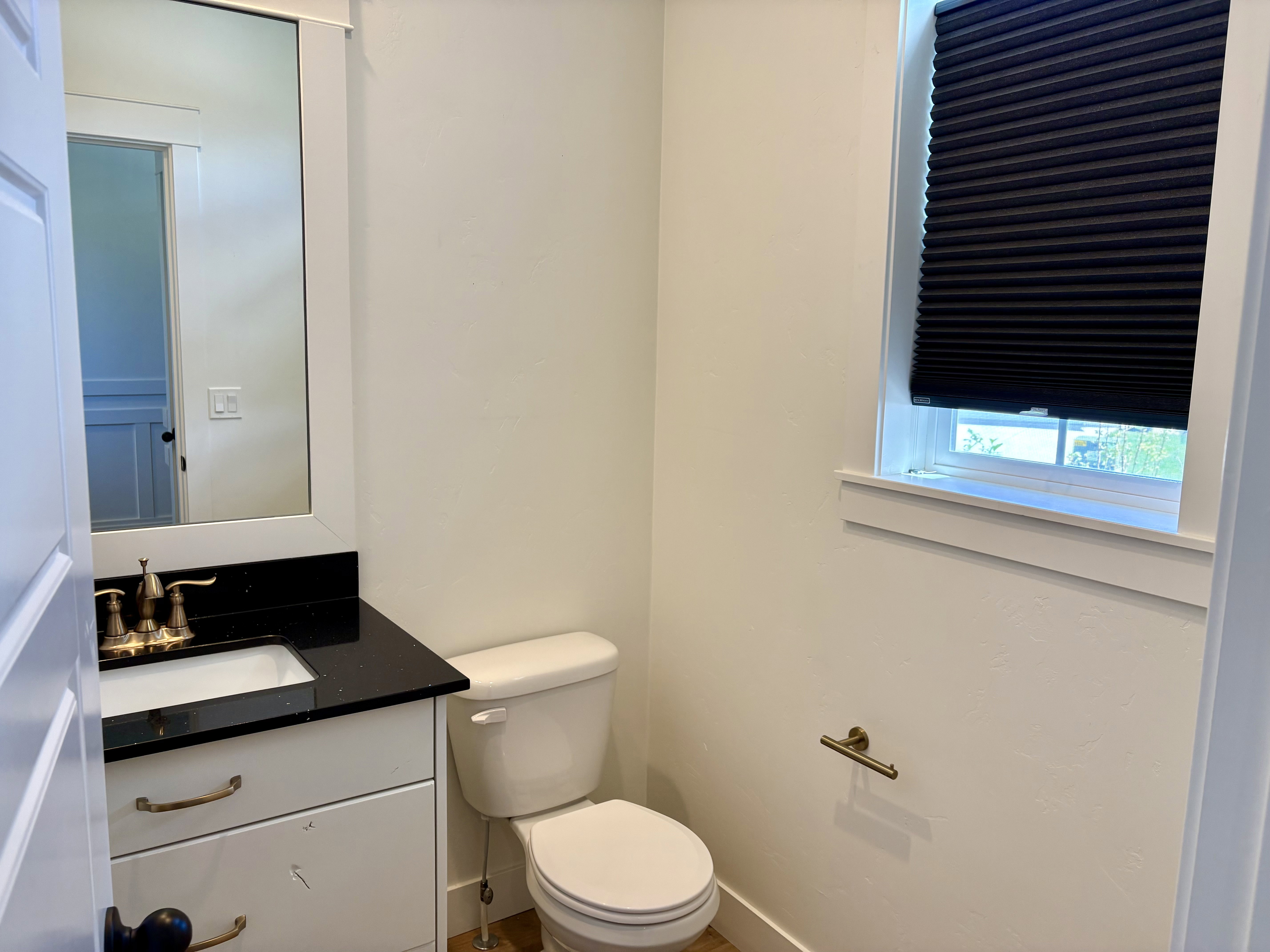 Bathroom featuring a white vanity with a black countertop, integrated sink, and bronze-finish faucet