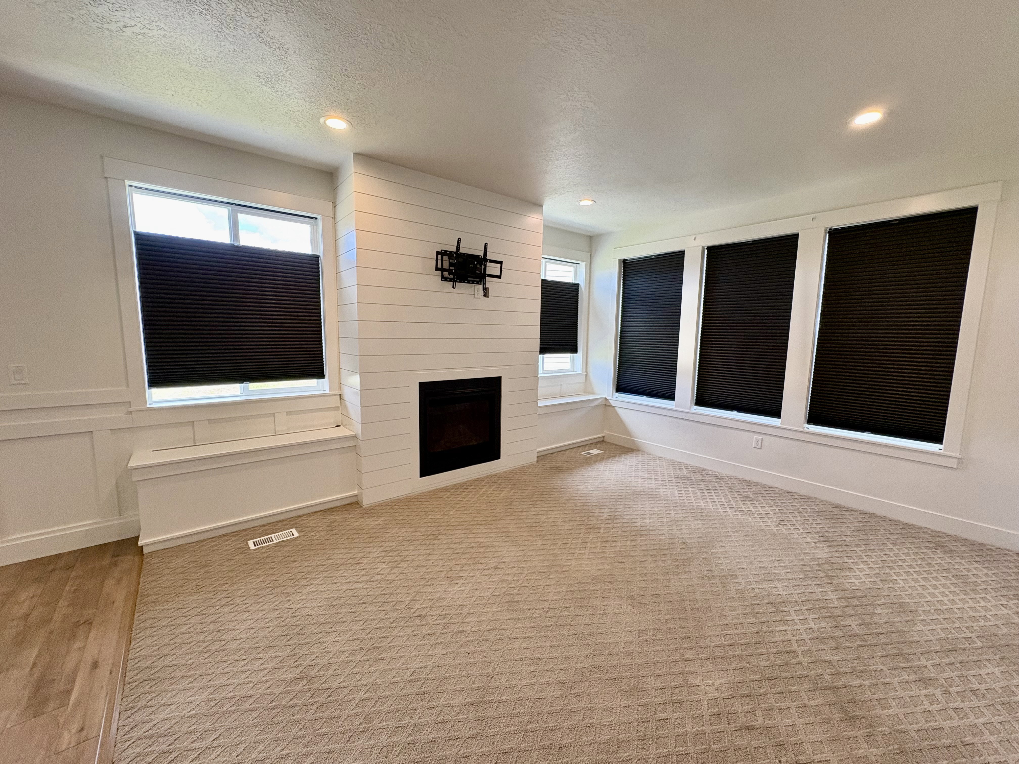 Living area featuring a modern fireplace with a shiplap surround, multiple windows with built-in window seats, recessed lighting, and patterned carpet flooring