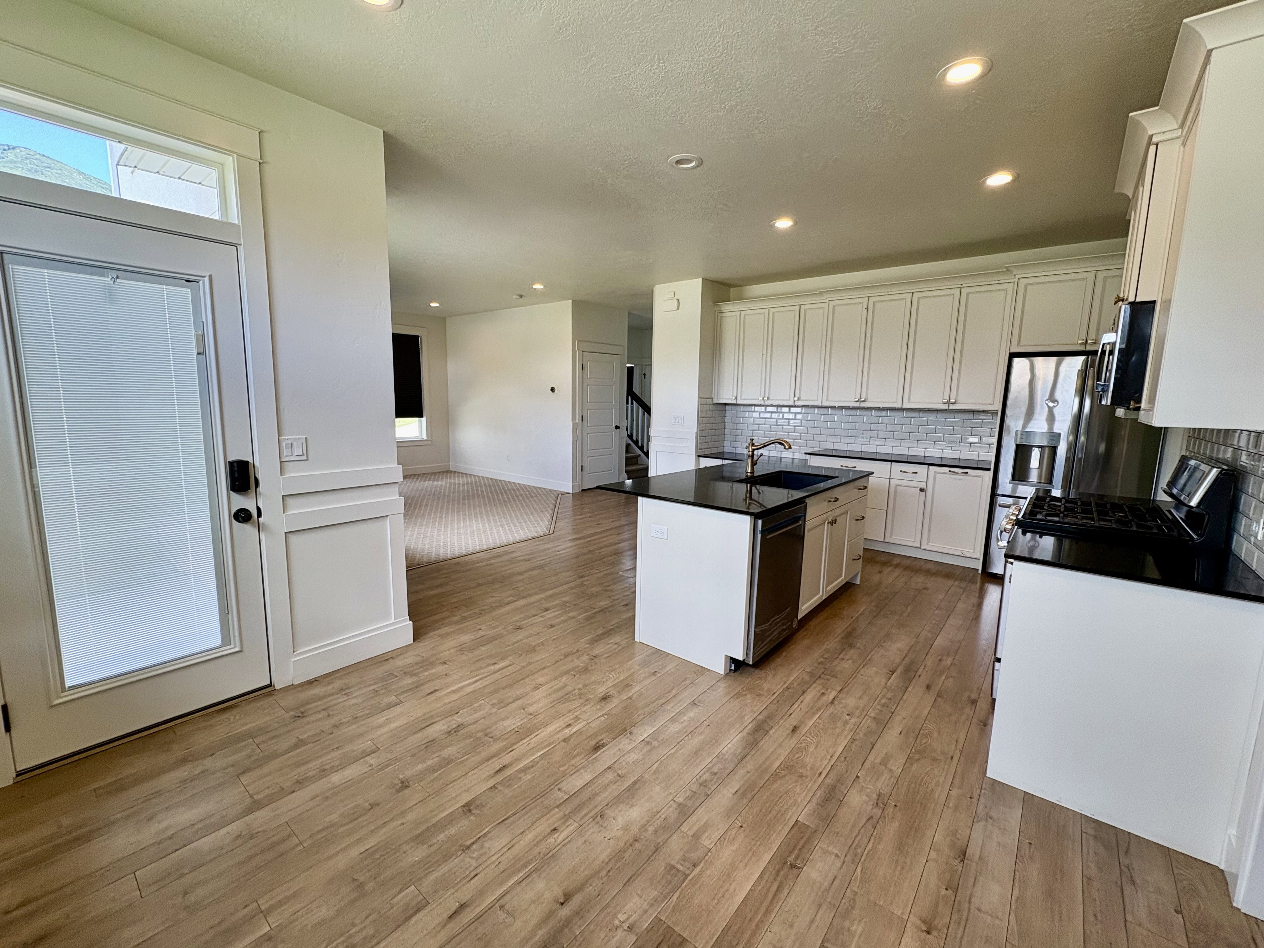 Contemporary kitchen featuring white cabinetry, dark countertops, and a subway tile backsplash