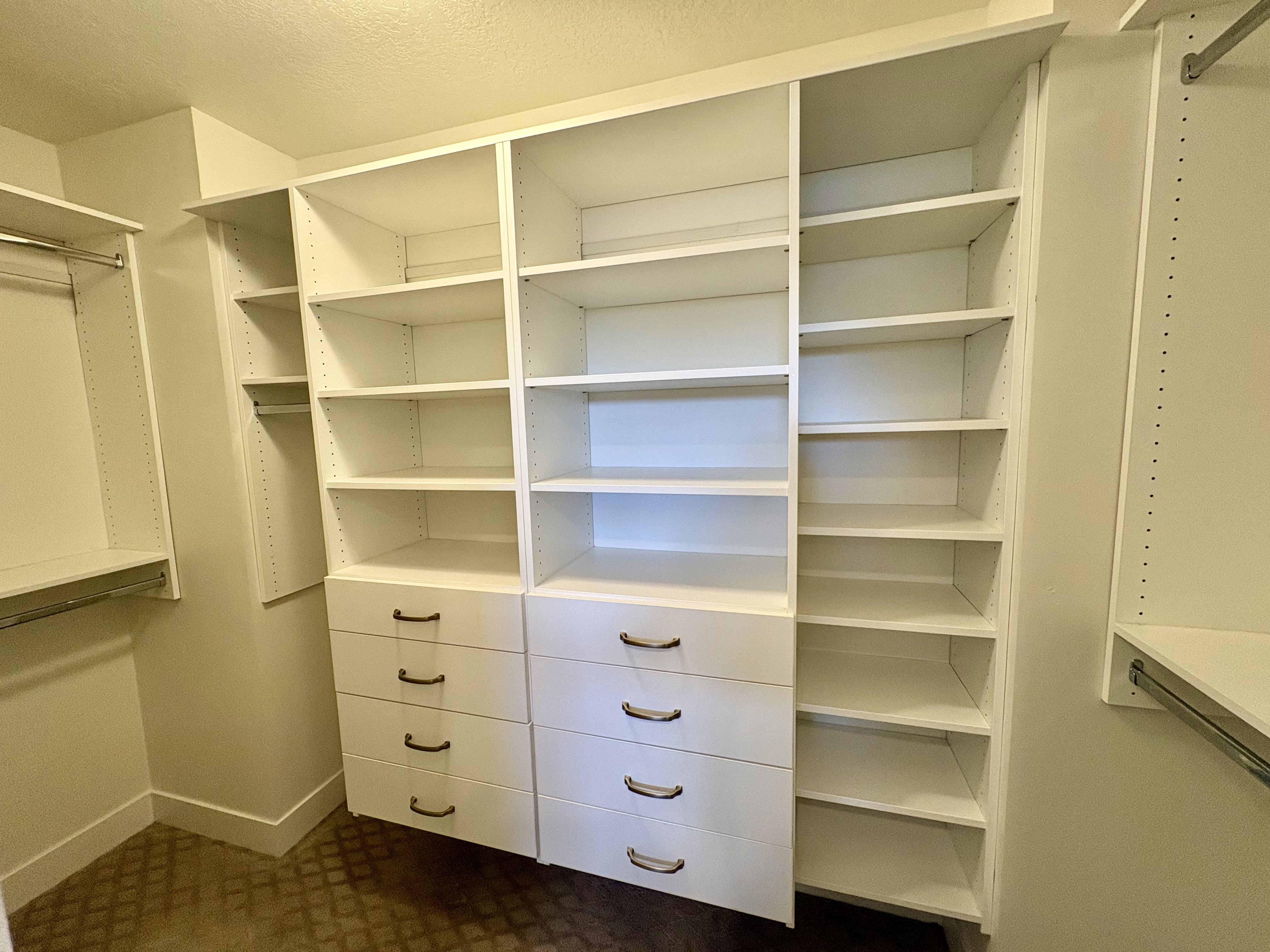 Custom closet system featuring extensive shelving, built-in drawers with modern hardware, and multiple hanging rods for optimized organization