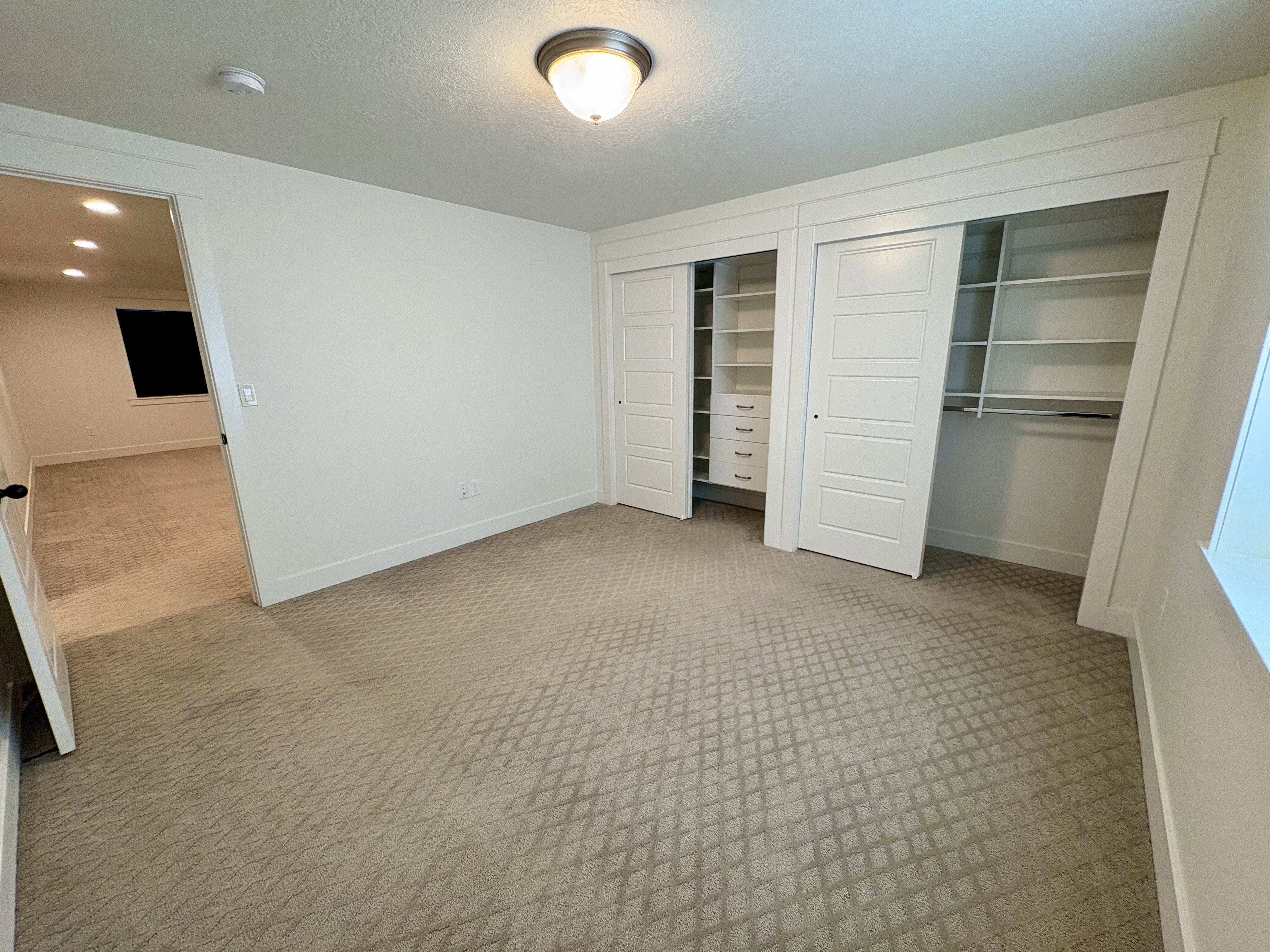 Large Bedroom featuring patterned carpeting and a built-in closet system with shelving, drawers, and hanging rods