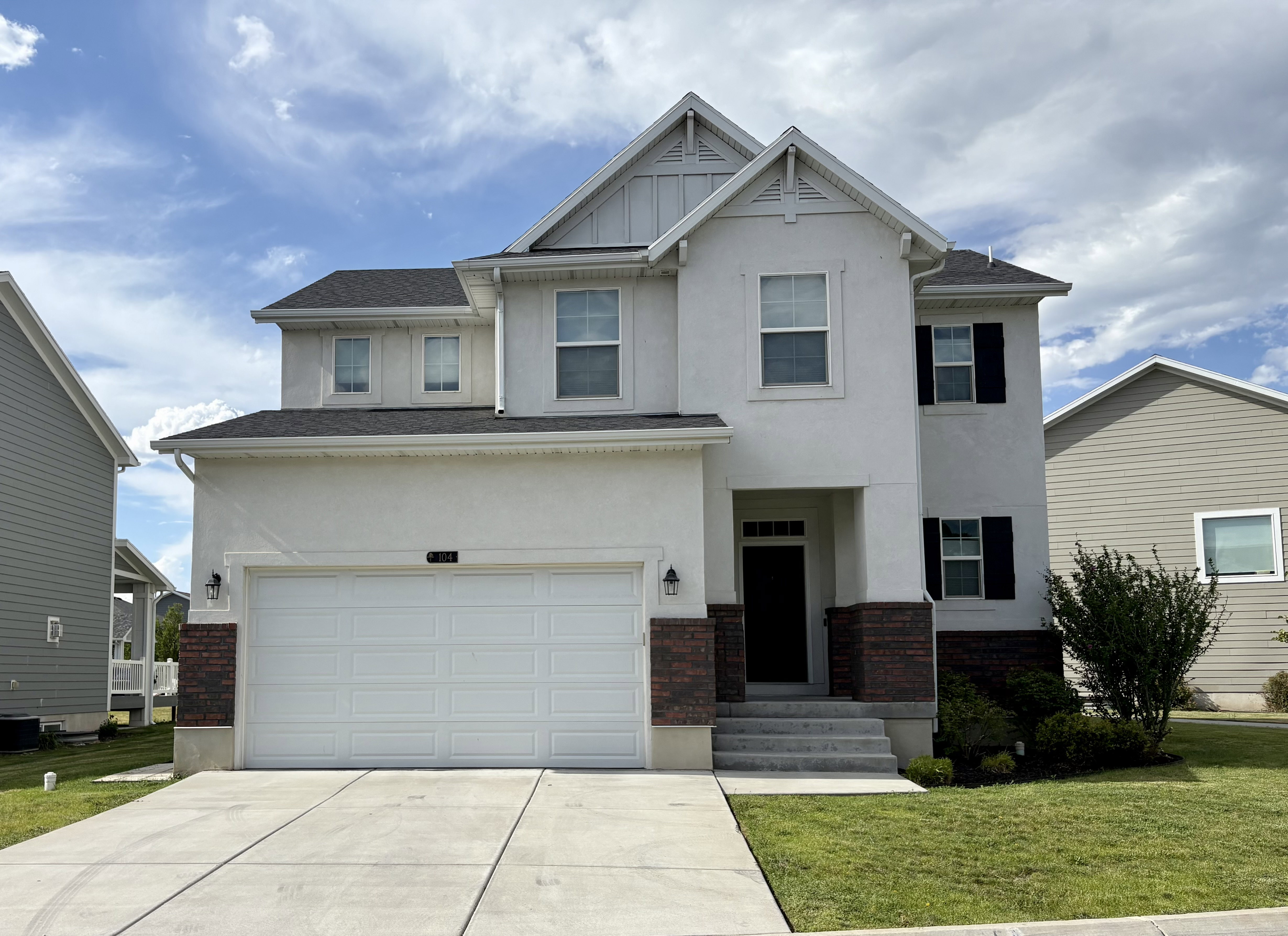 Contemporary two-story residence featuring a white stucco facade with dark brick accents