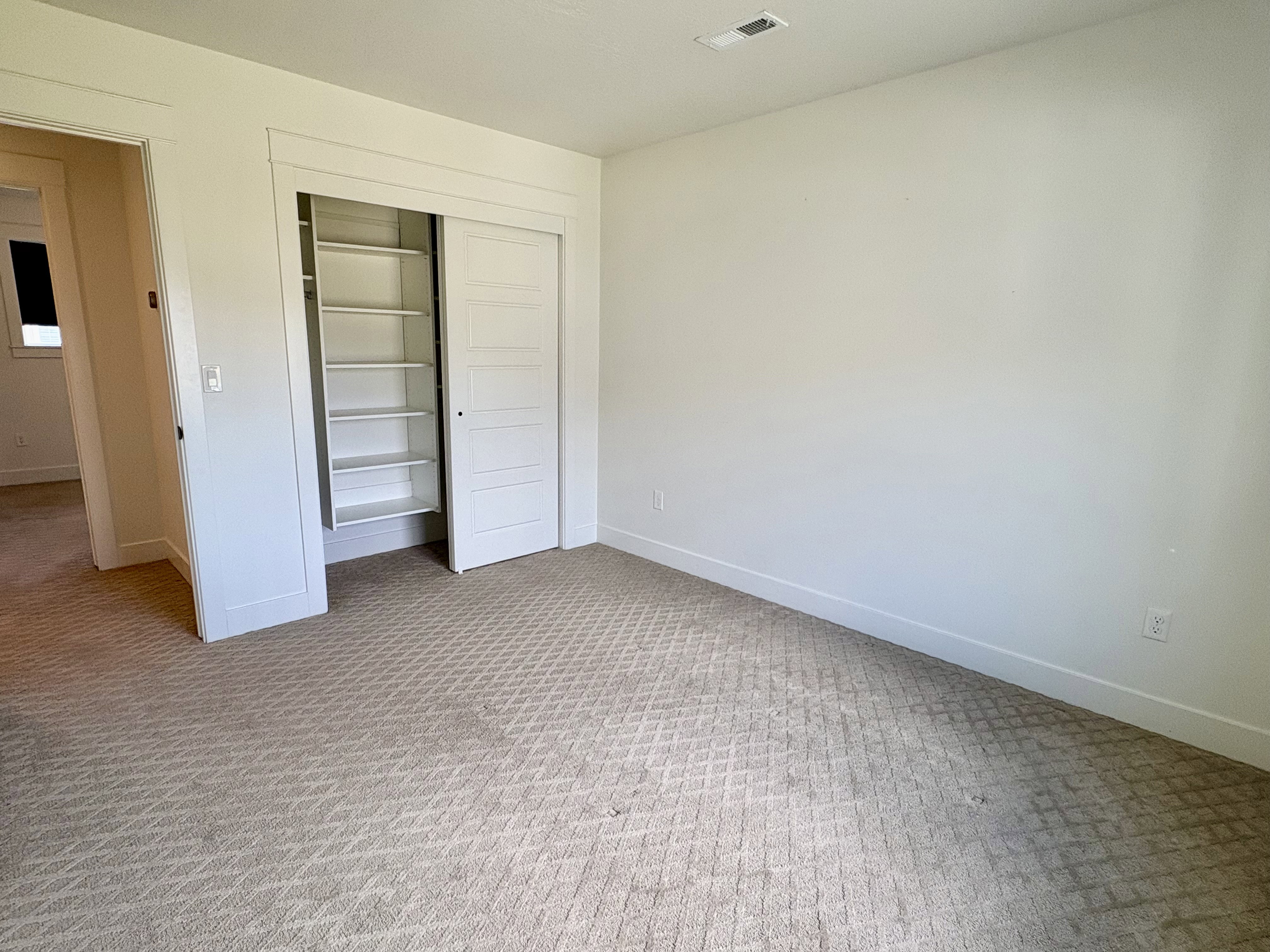 Bedroom featuring patterned carpet flooring, white walls, and a built-in closet with sliding panel doors and integrated shelving
