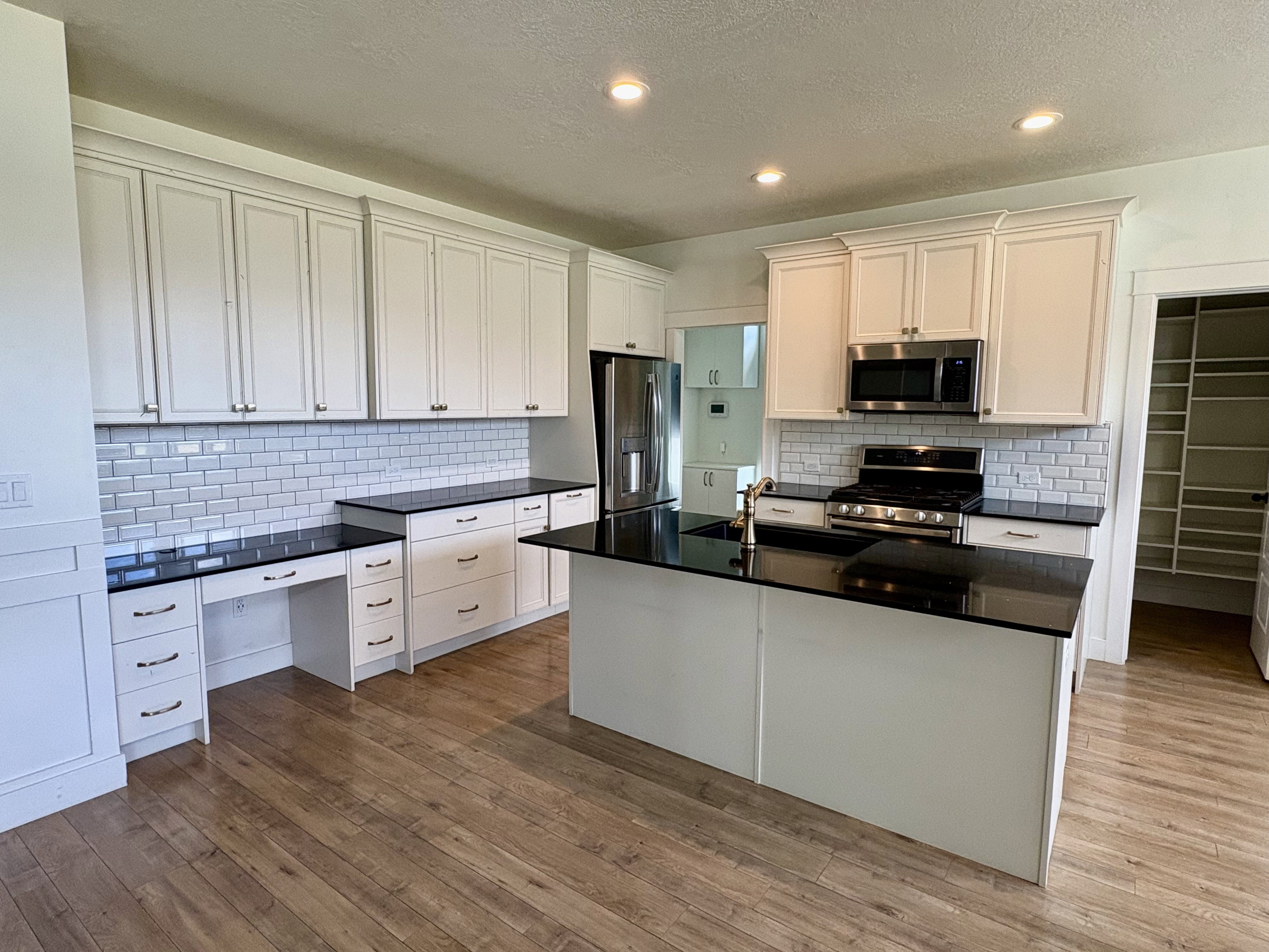 Modern kitchen featuring shaker-style white cabinetry, black countertops, and a white subway tile backsplash