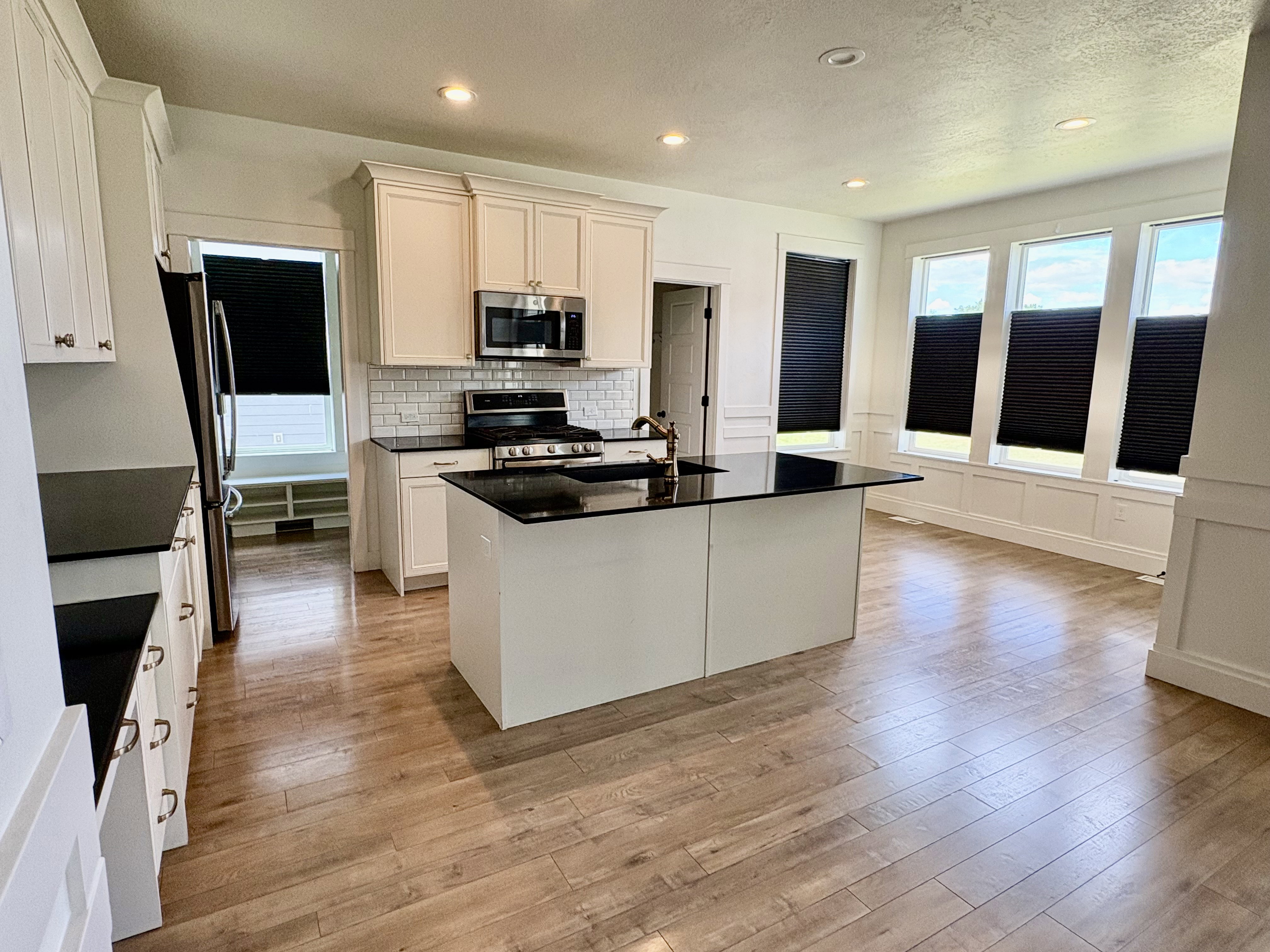 Kitchen featuring a central island with a dark countertop, white cabinetry, stainless steel appliances, and a subway tile backsplash