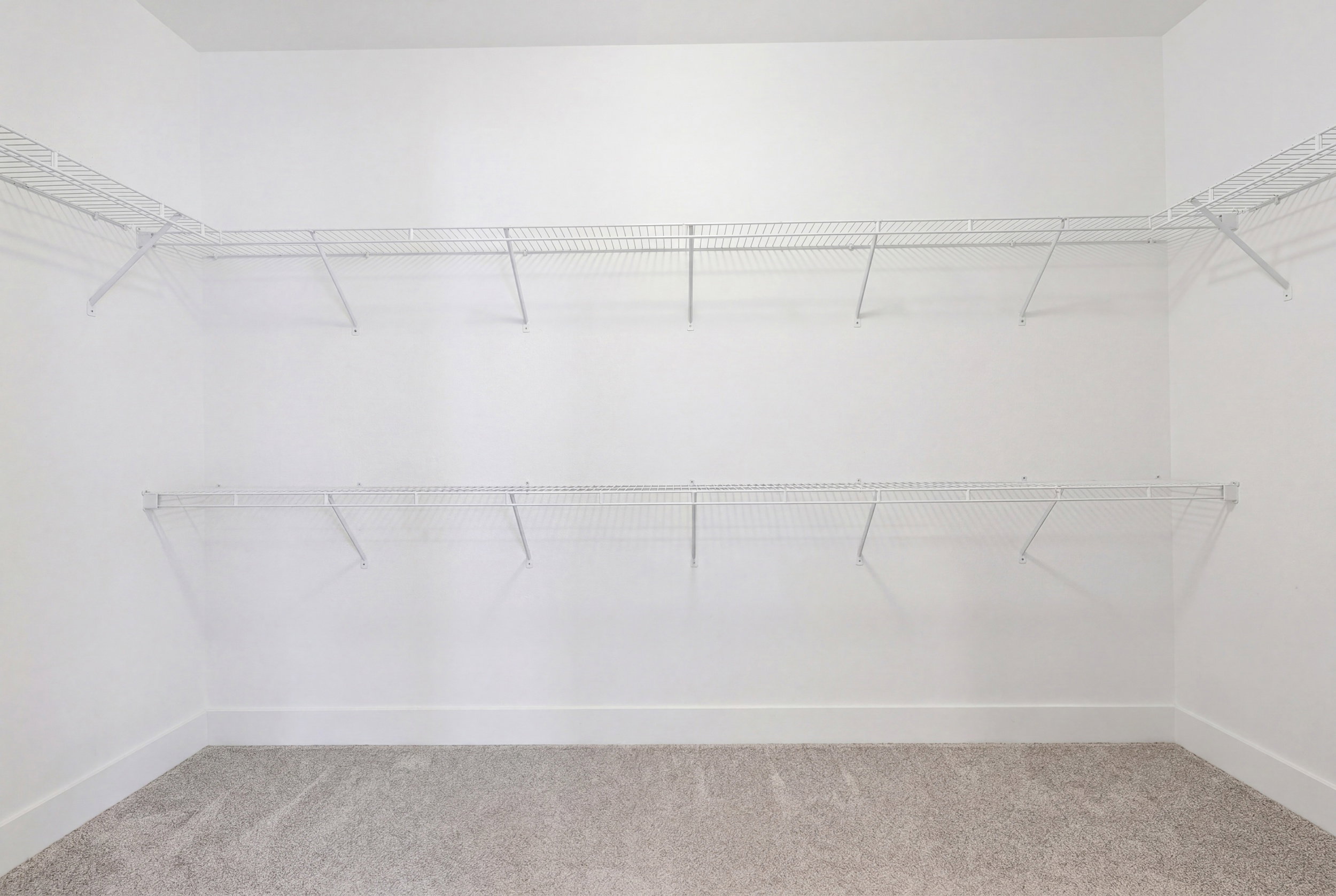 Carpeted room with white walls, white baseboards, and two levels of white wire shelving