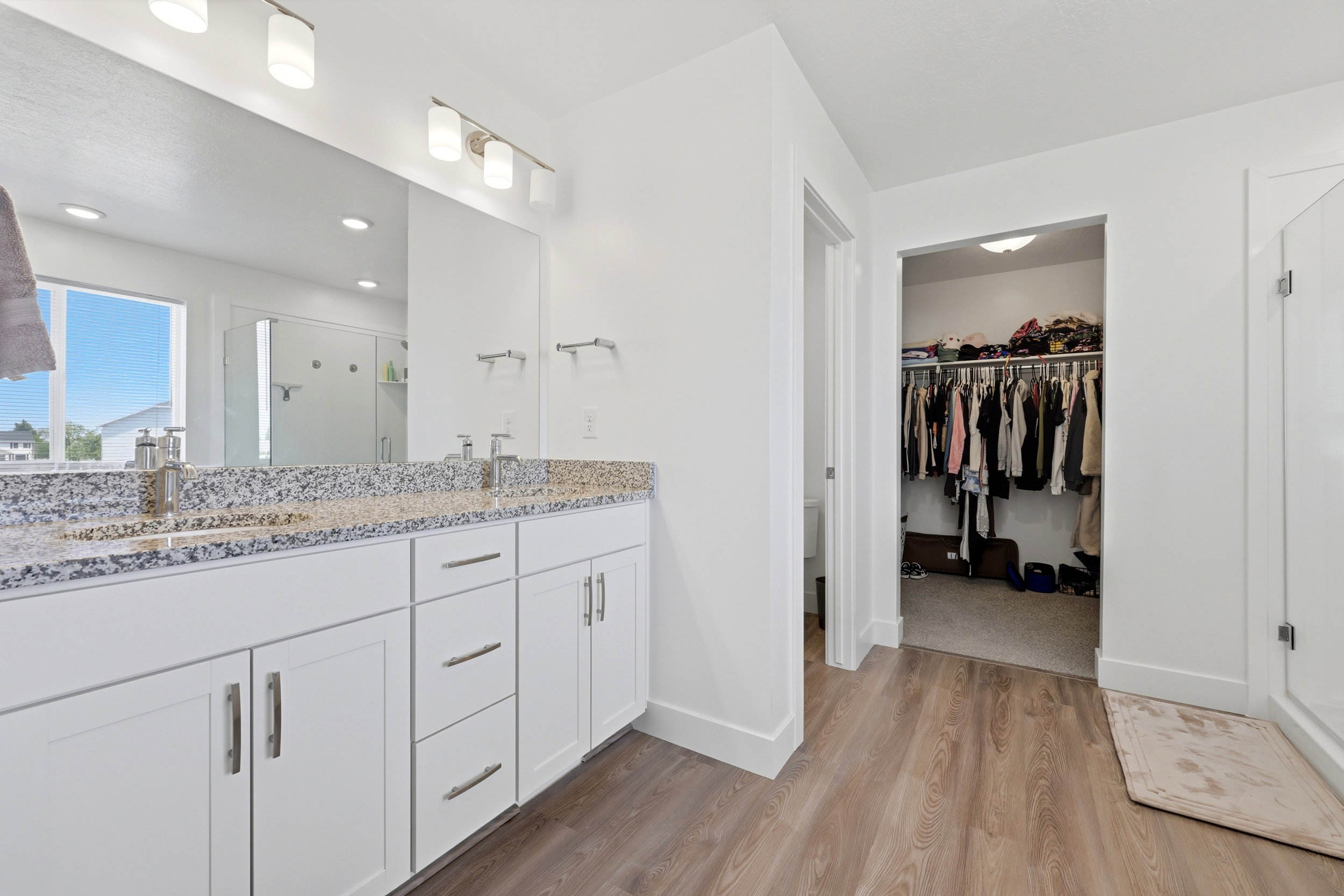 Double vanity with white cabinetry, granite-finish countertop, and undermount sinks
