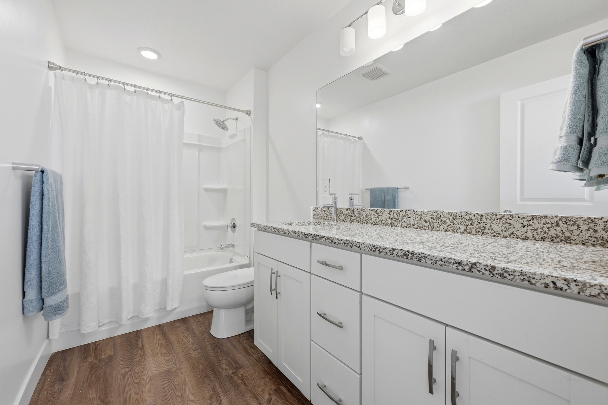 Bathroom featuring a white vanity with granite-style countertop, undermount sink, and contemporary fixtures