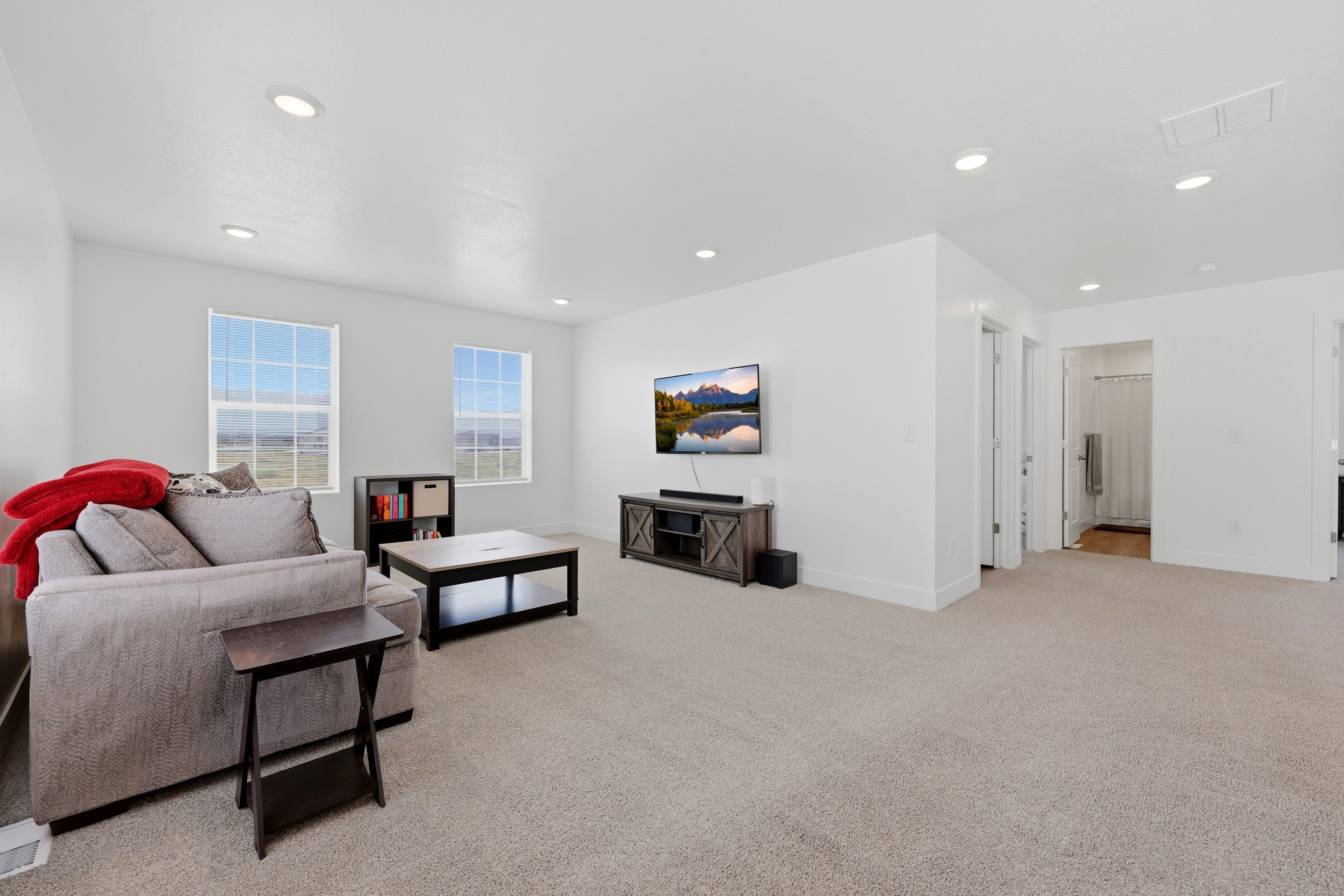 Spacious carpeted room featuring white walls and recessed lighting