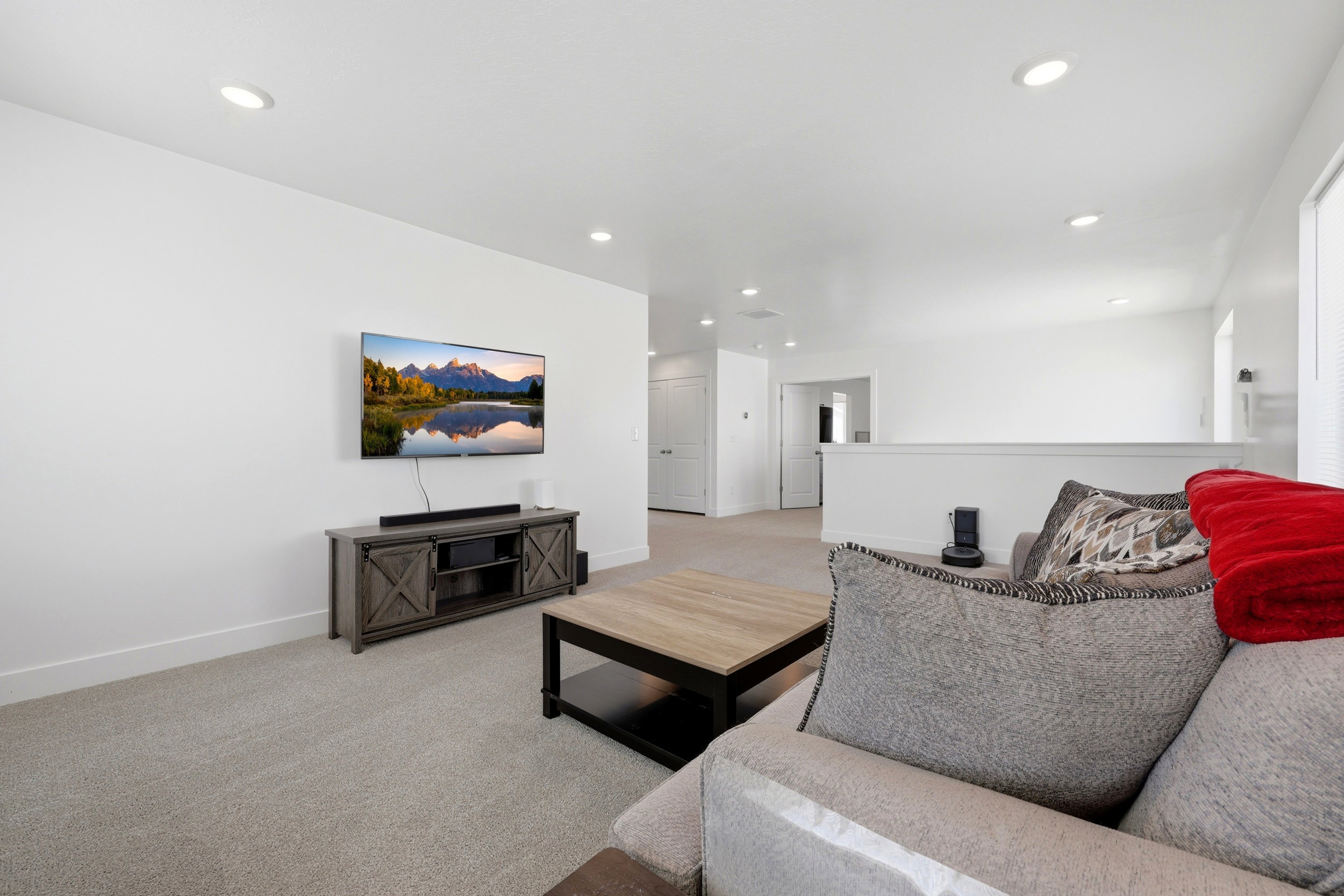 Recessed lighting illuminates neutral carpeting and white walls
