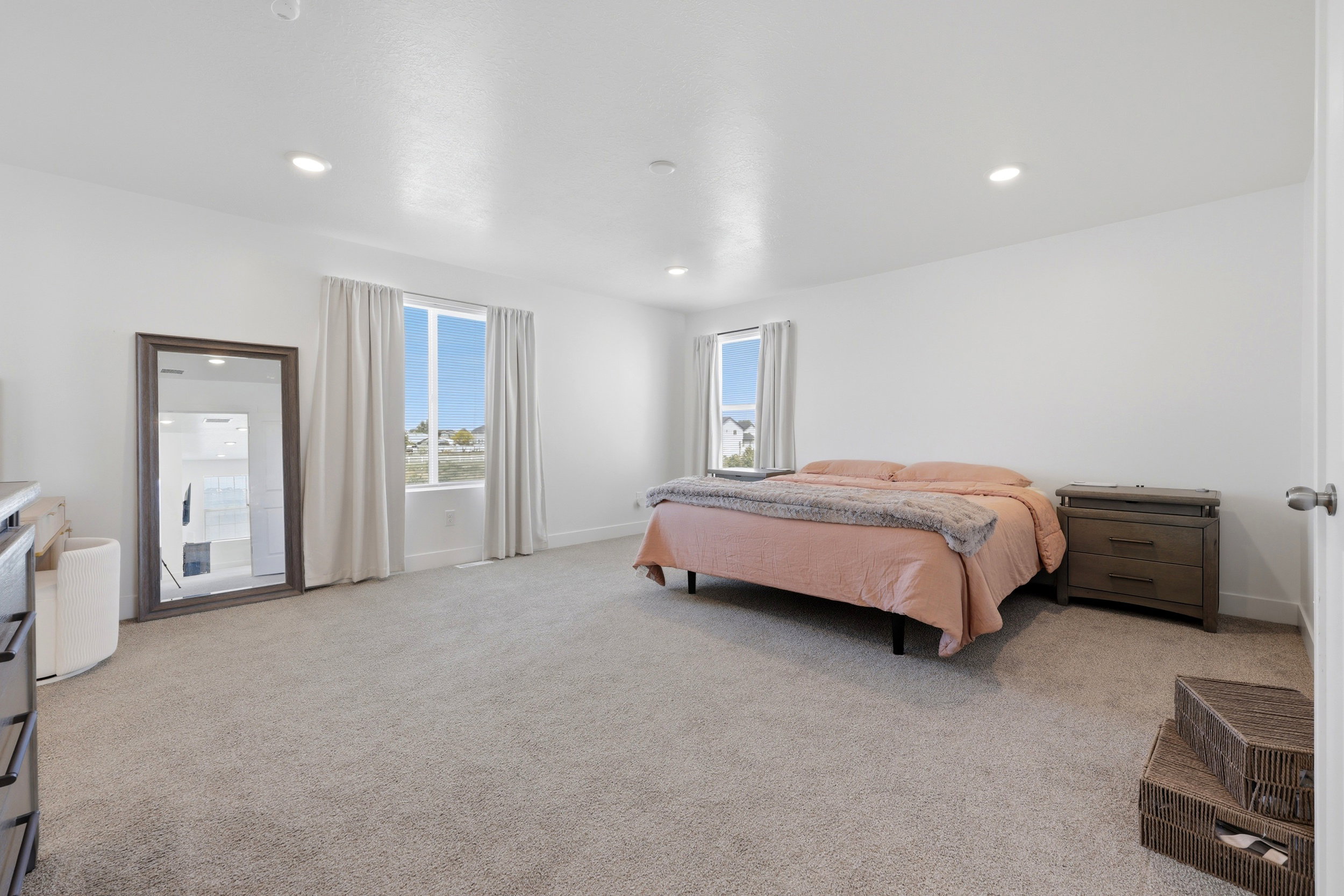 Spacious room featuring light-toned carpeting, white walls, and recessed lighting