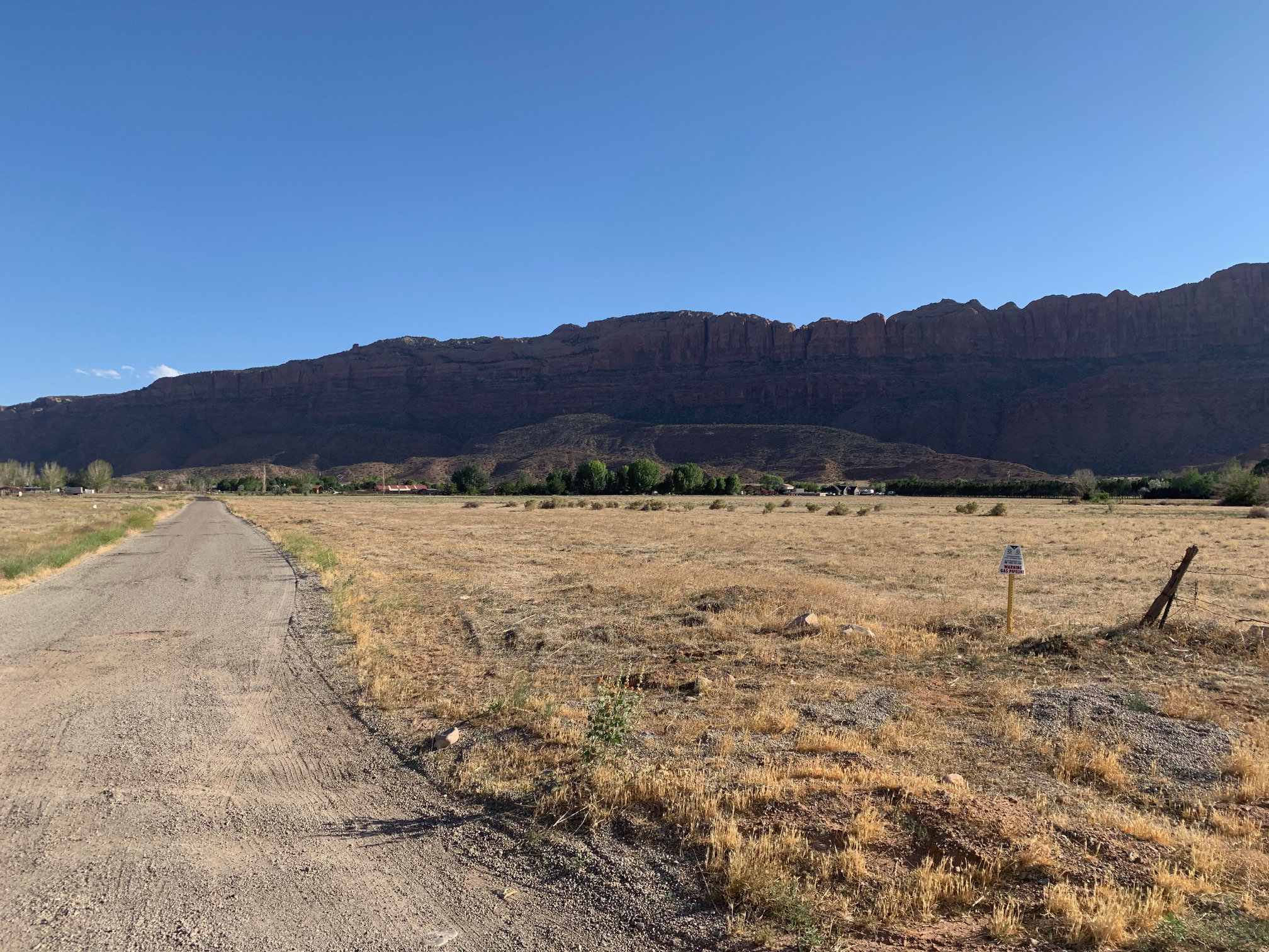 Expansive open land featuring a paved road, natural vegetation, and distant mountain range