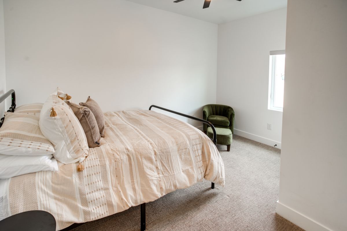 Bedroom featuring a large window, neutral carpeting, and a ceiling fan